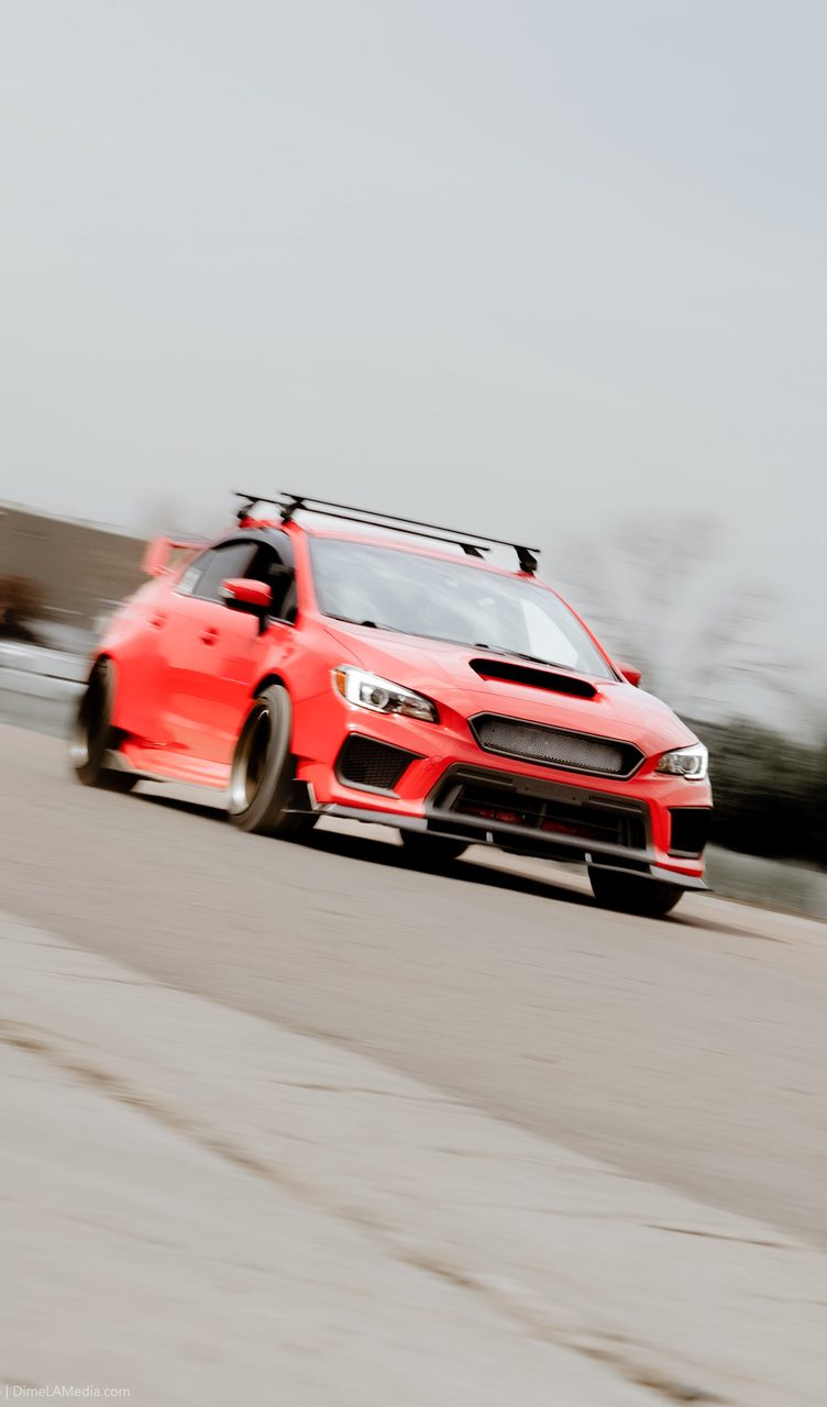 Red Subaru WRX STI panning shot in motion on a Sioux Falls road