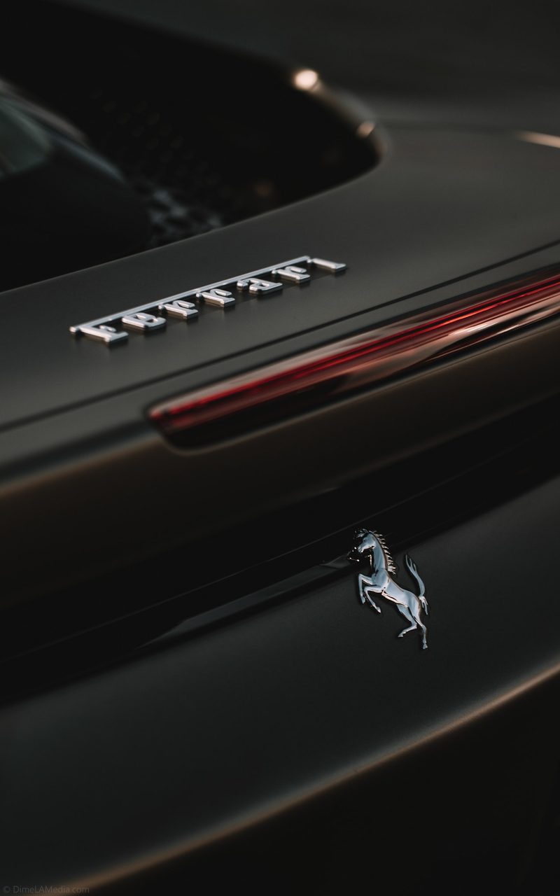 Chrome Ferrari script and prancing horse badge on a matte black engine cover
