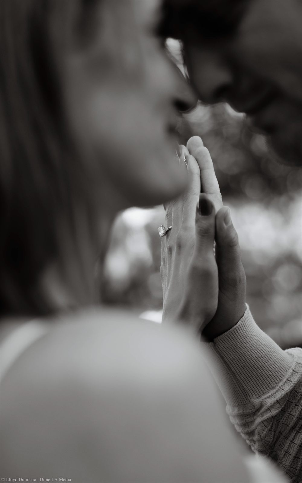 Black and white close-up of a couple's hands and engagement ring