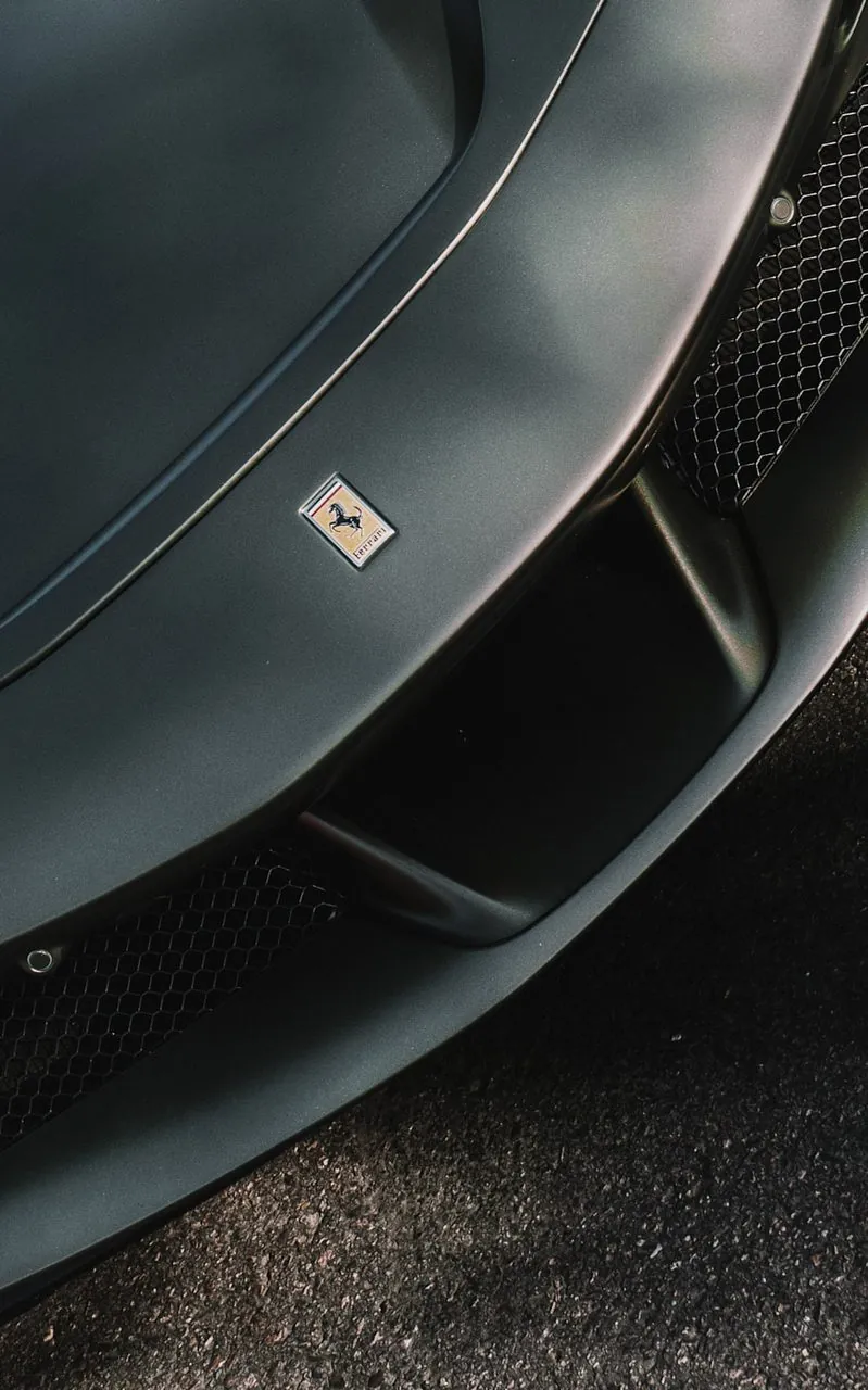 Overhead detail of the Ferrari badge and carbon front splitter on a red F8
