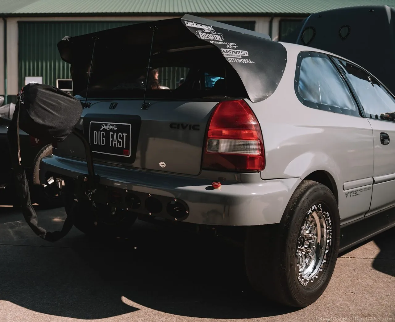 Drag-prepped Honda Civic hatchback with a tall wing at a car show