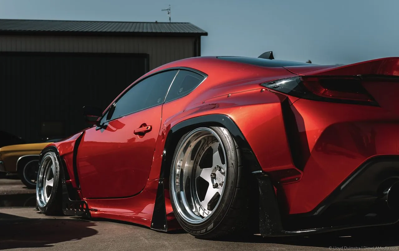 Candy-red widebody Toyota GR86 rear three-quarter on deep-dish wheels