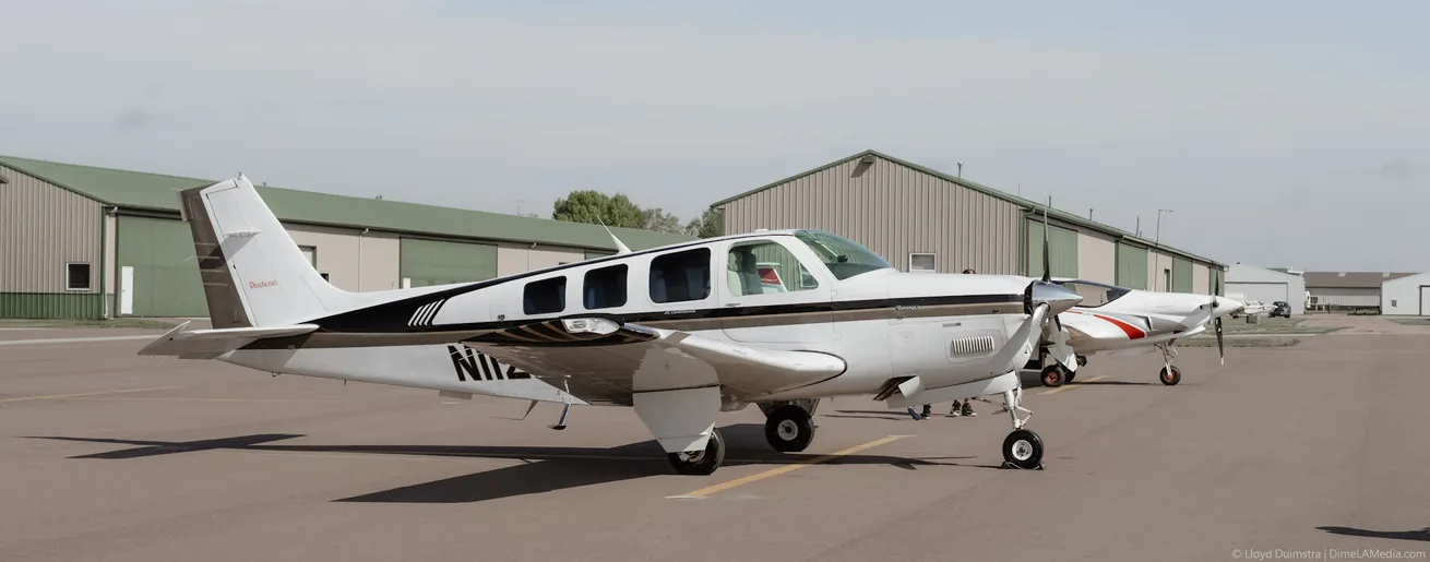 Beechcraft Bonanza aircraft parked on the ramp outside a hangar