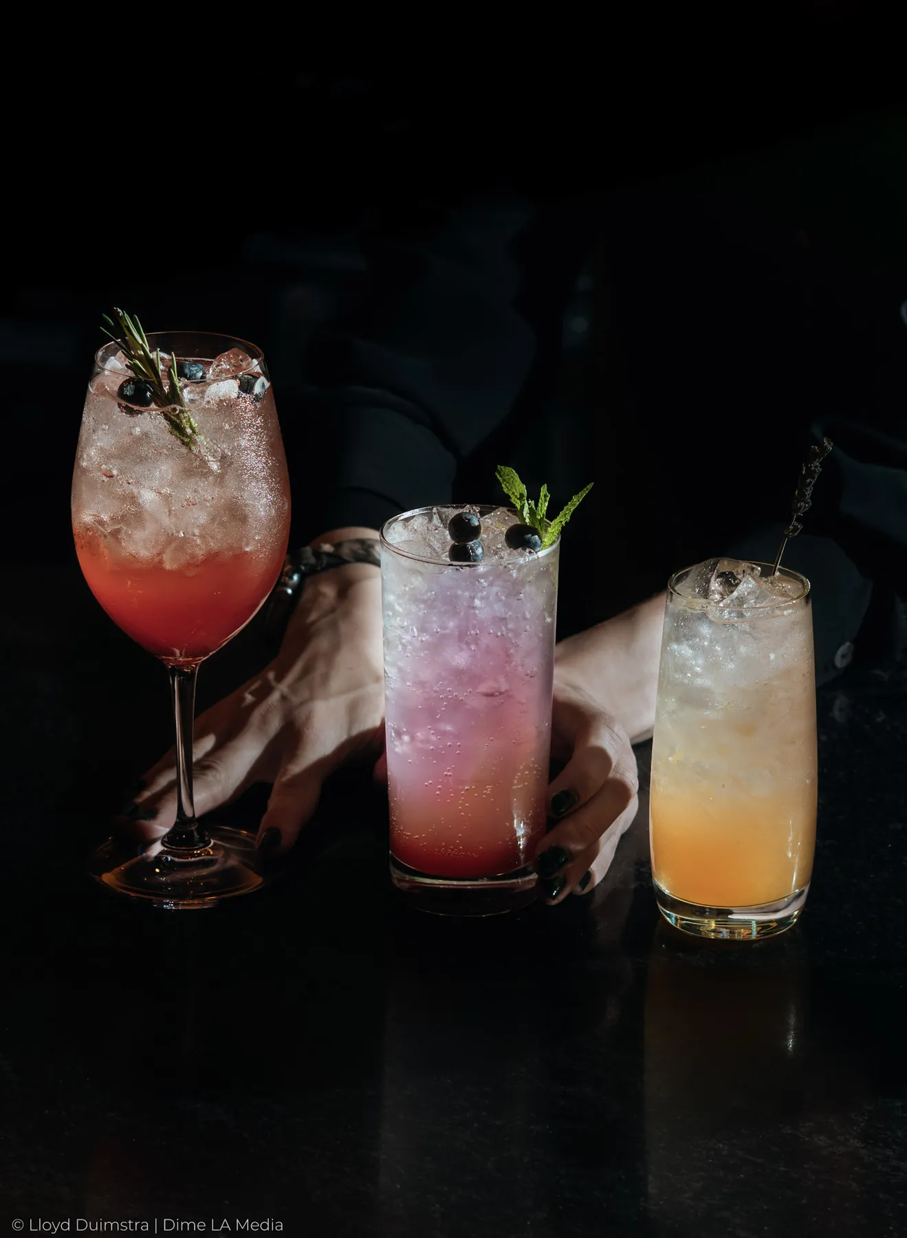 Three cocktails served together as a bartender sets them on the bar
