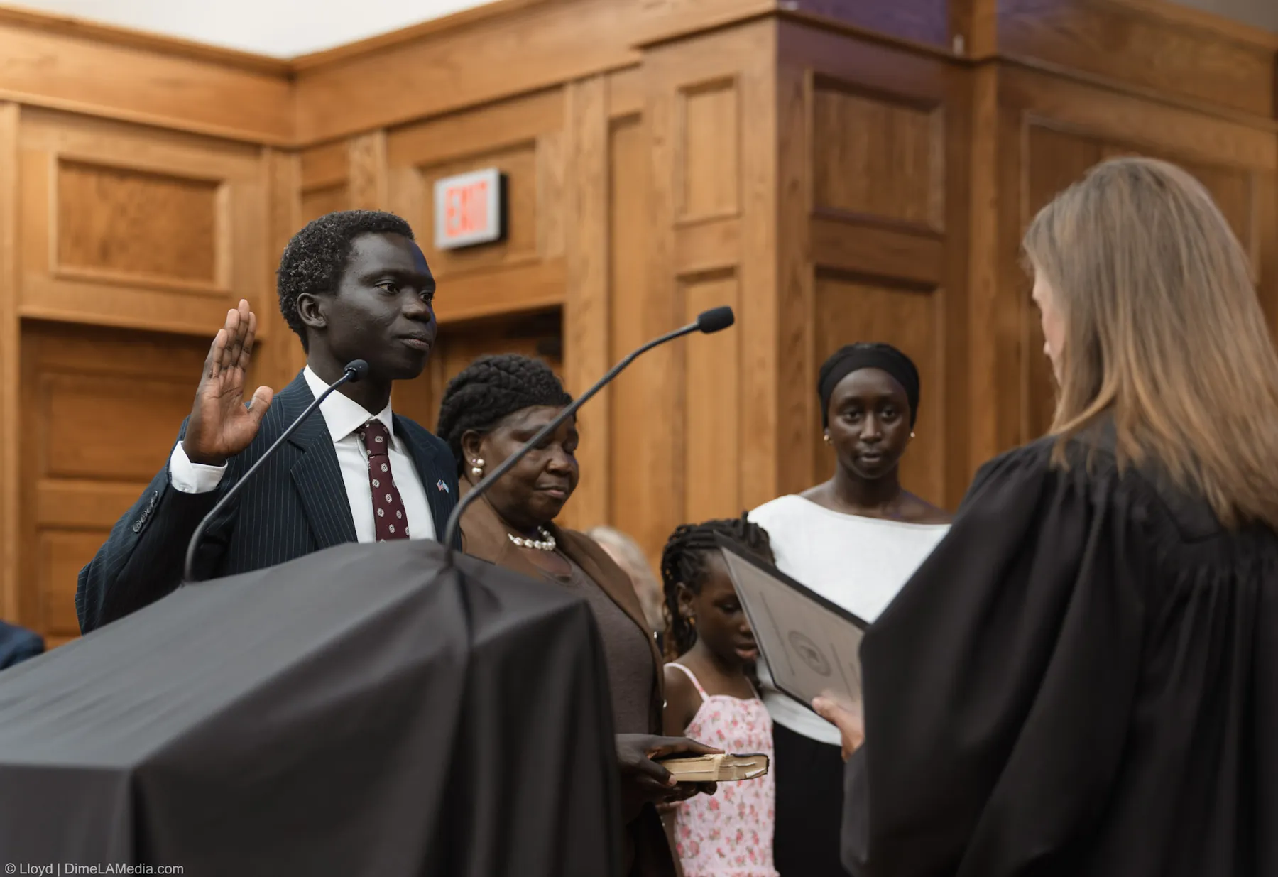 Zak Okuwe raises his right hand for the oath as his family holds the Bible beside him