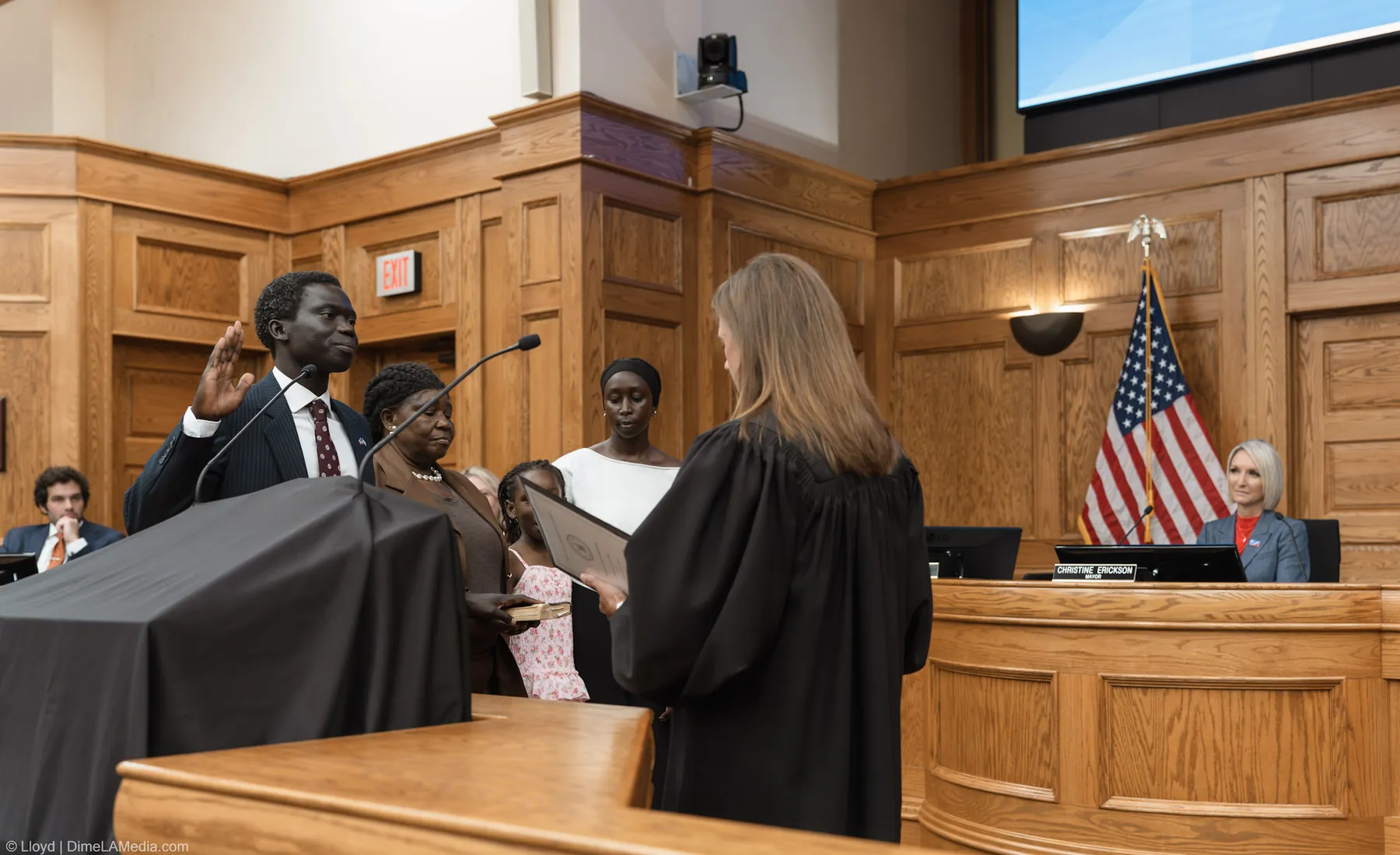 Zak Okuwe takes the council oath of office with his family beside him as Mayor Christine Erickson watches from the dais