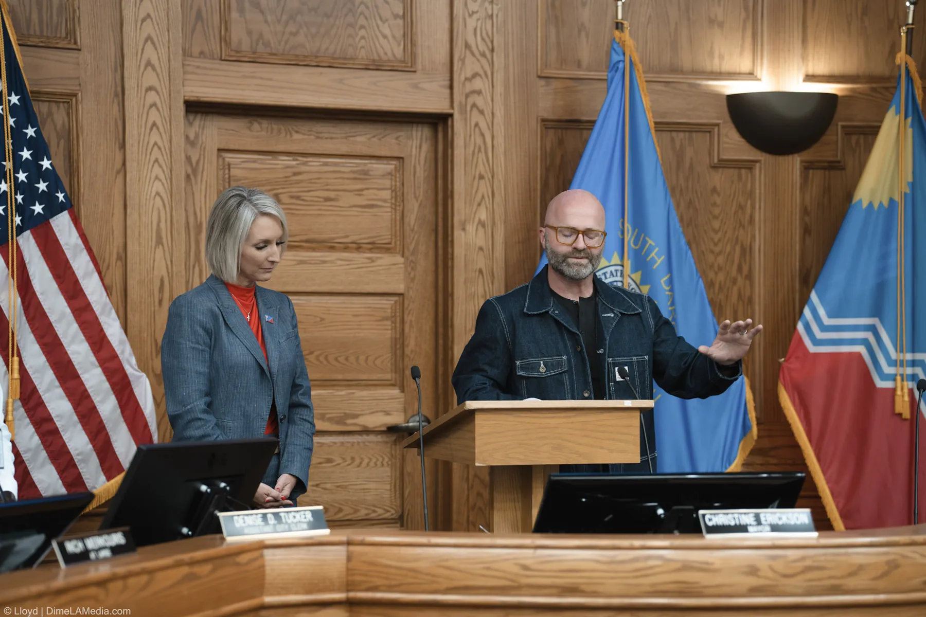 Pastor Adam Weber of Embrace Church prays over the ceremony as Mayor Erickson bows her head