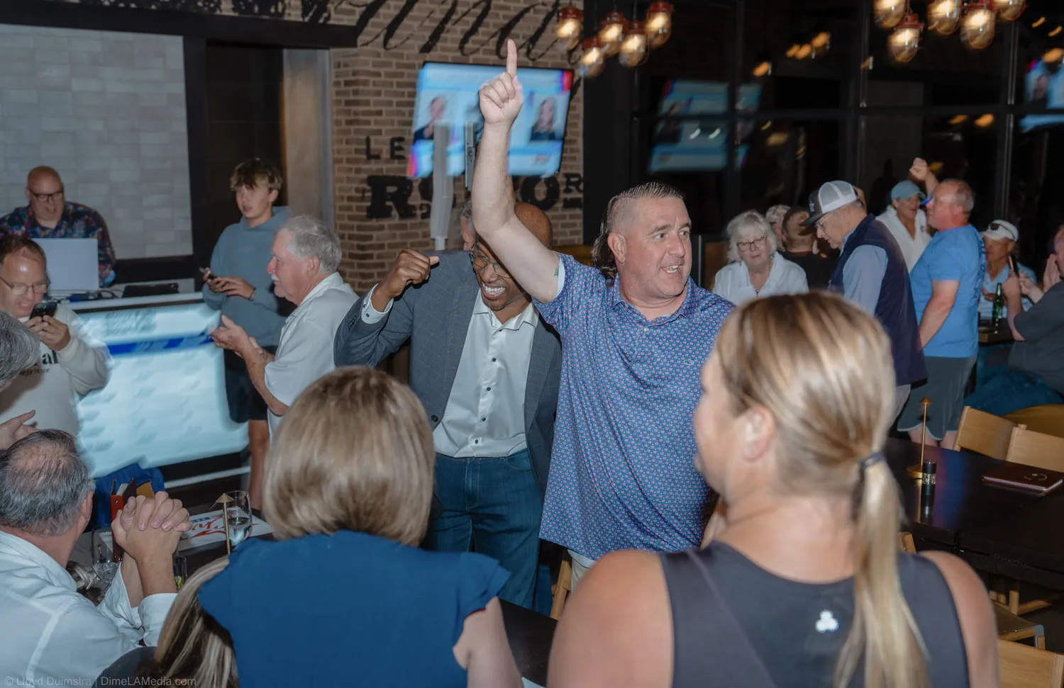 A supporter throws his arms up in celebration as Christine Erickson takes the lead