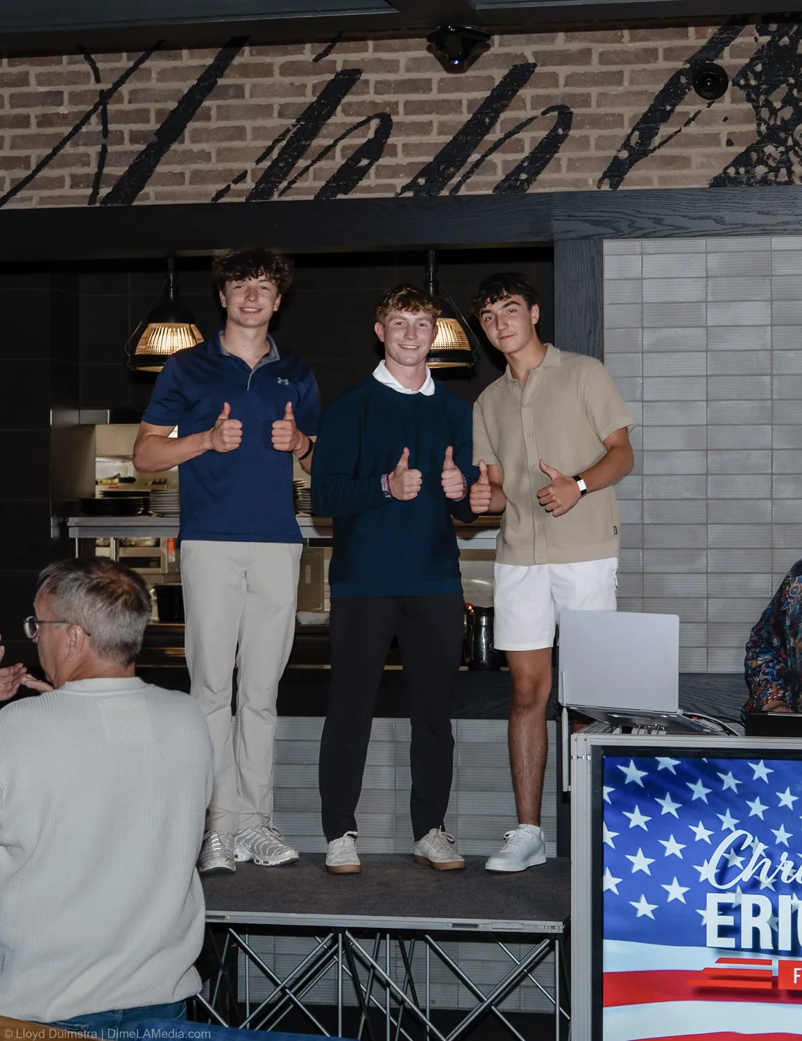 Christine Erickson's sons give thumbs up on stage at the victory party