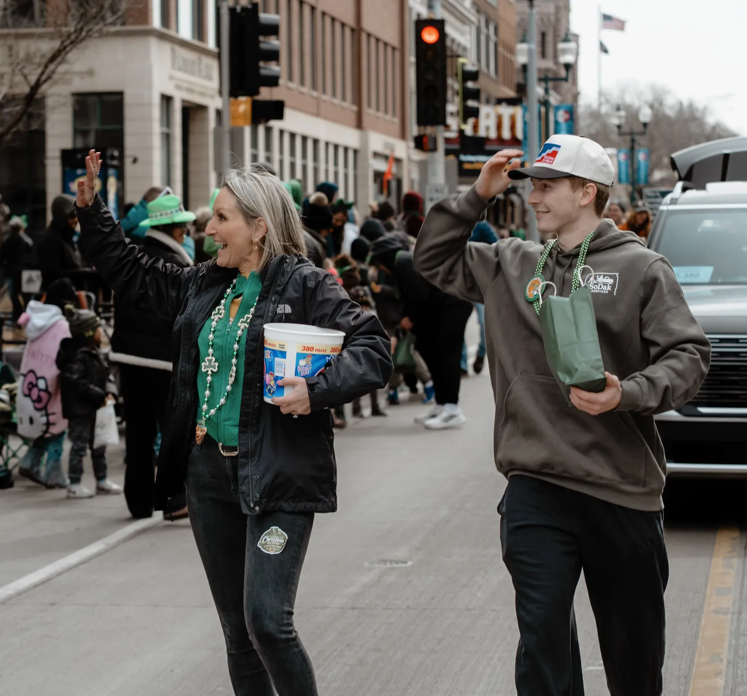 Christine Erickson waves to the crowd while walking the St. Patrick's Day parade route in Sioux Falls