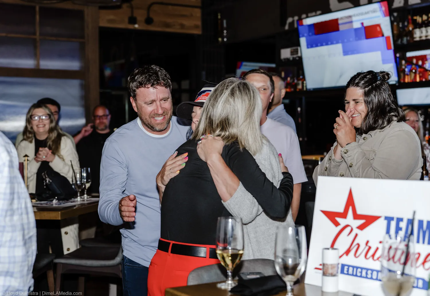 Christine Erickson embraces a supporter next to a Team Christine campaign sign
