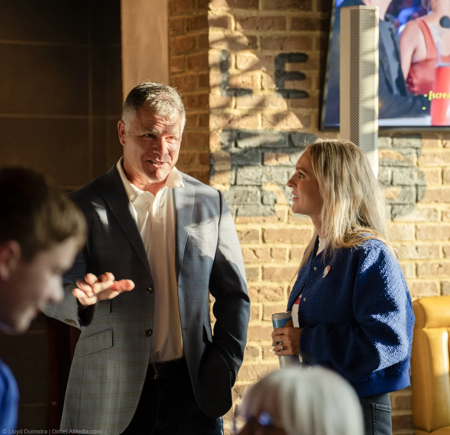 Two supporters in conversation in golden hour light at the watch party