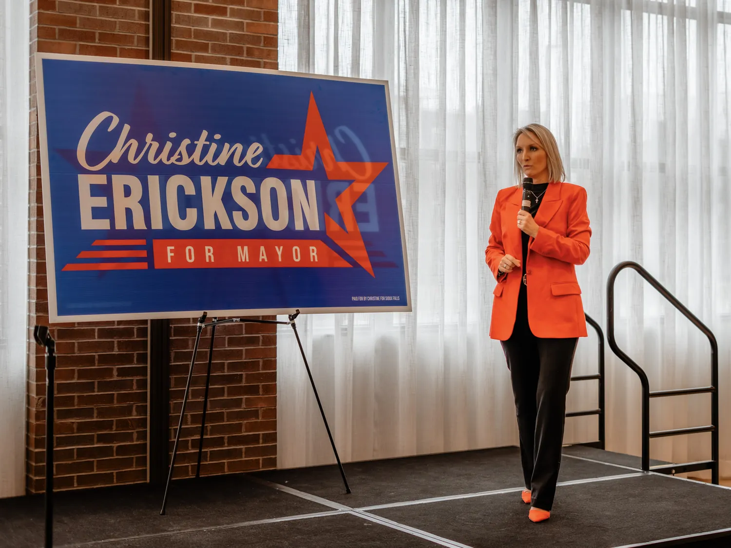 Christine Erickson walks past her Christine Erickson for Mayor campaign sign at a campaign event in Sioux Falls