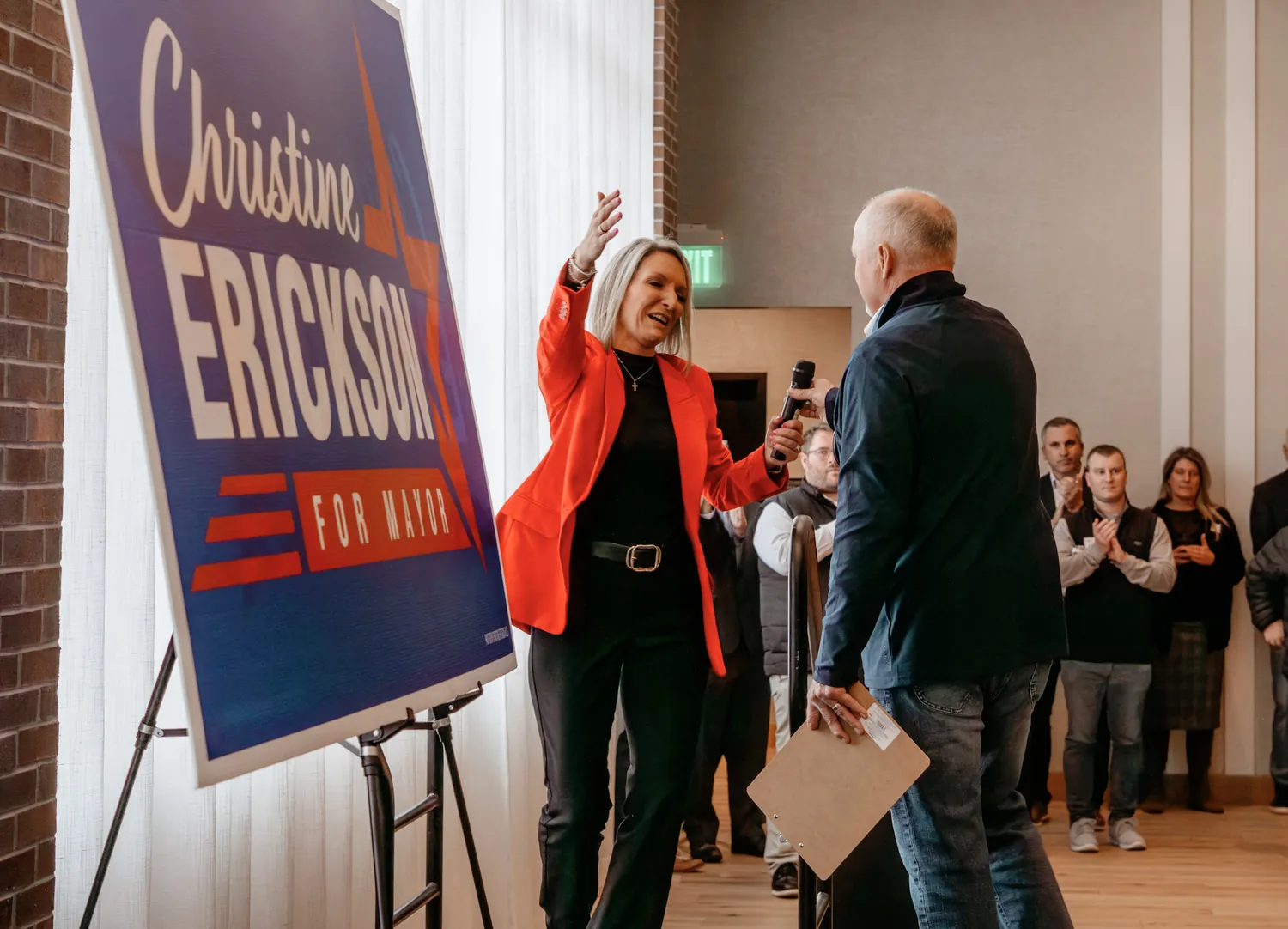 Christine Erickson high-fives a supporter in front of her campaign sign at a Sioux Falls rally