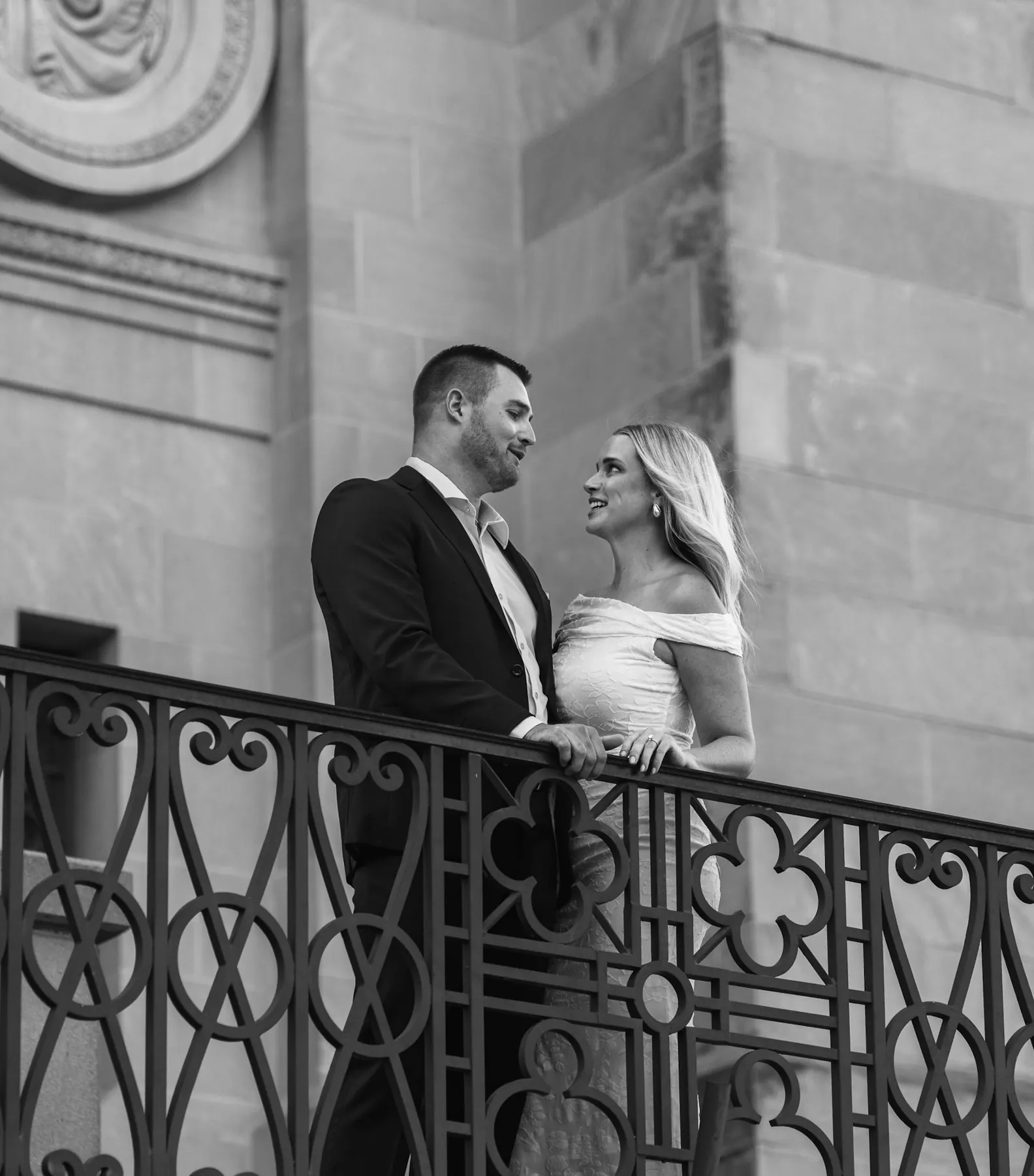 Black and white engagement portrait behind a wrought-iron railing, Sioux Falls SD