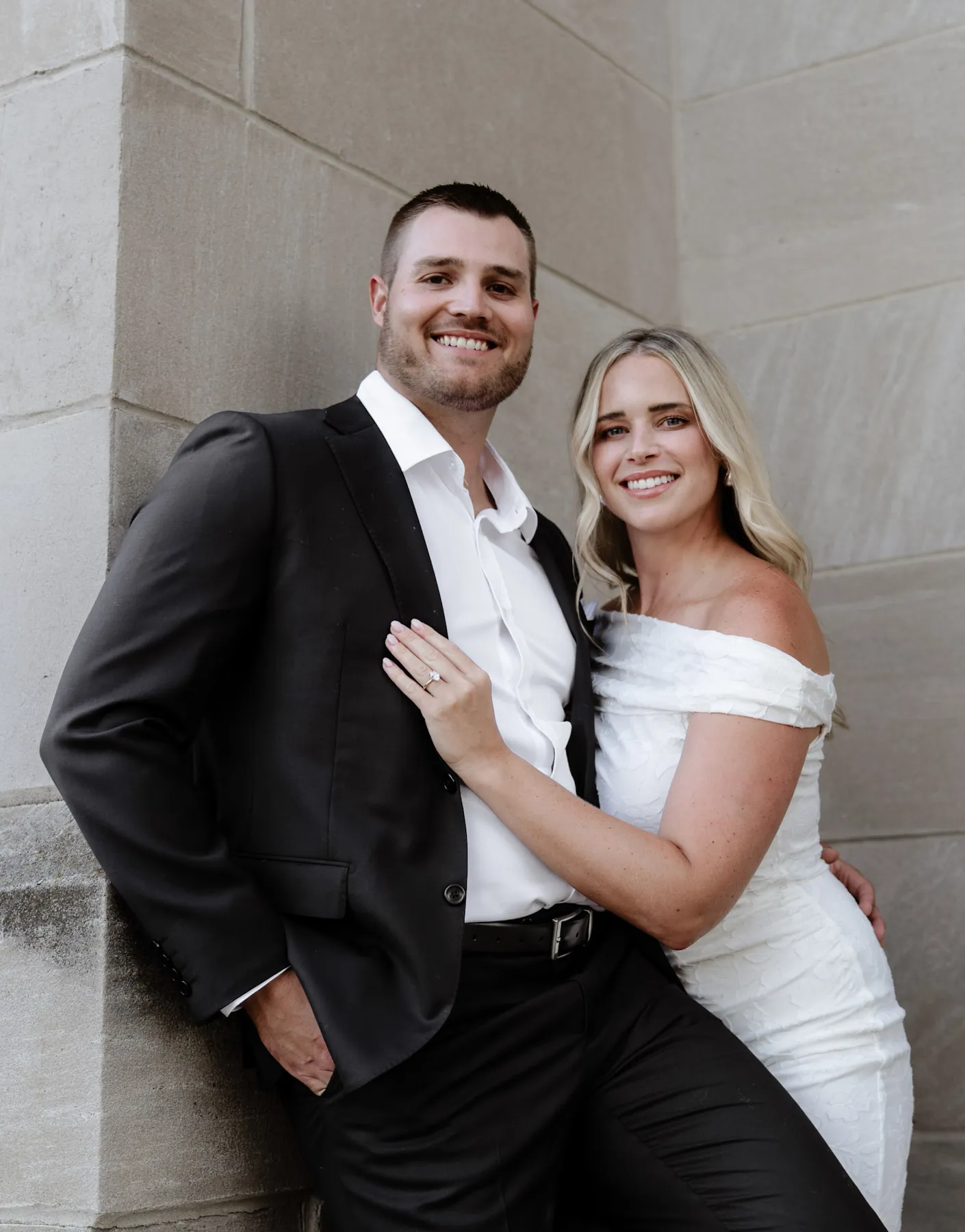 Engaged couple smiling against the cathedral limestone in Sioux Falls, SD