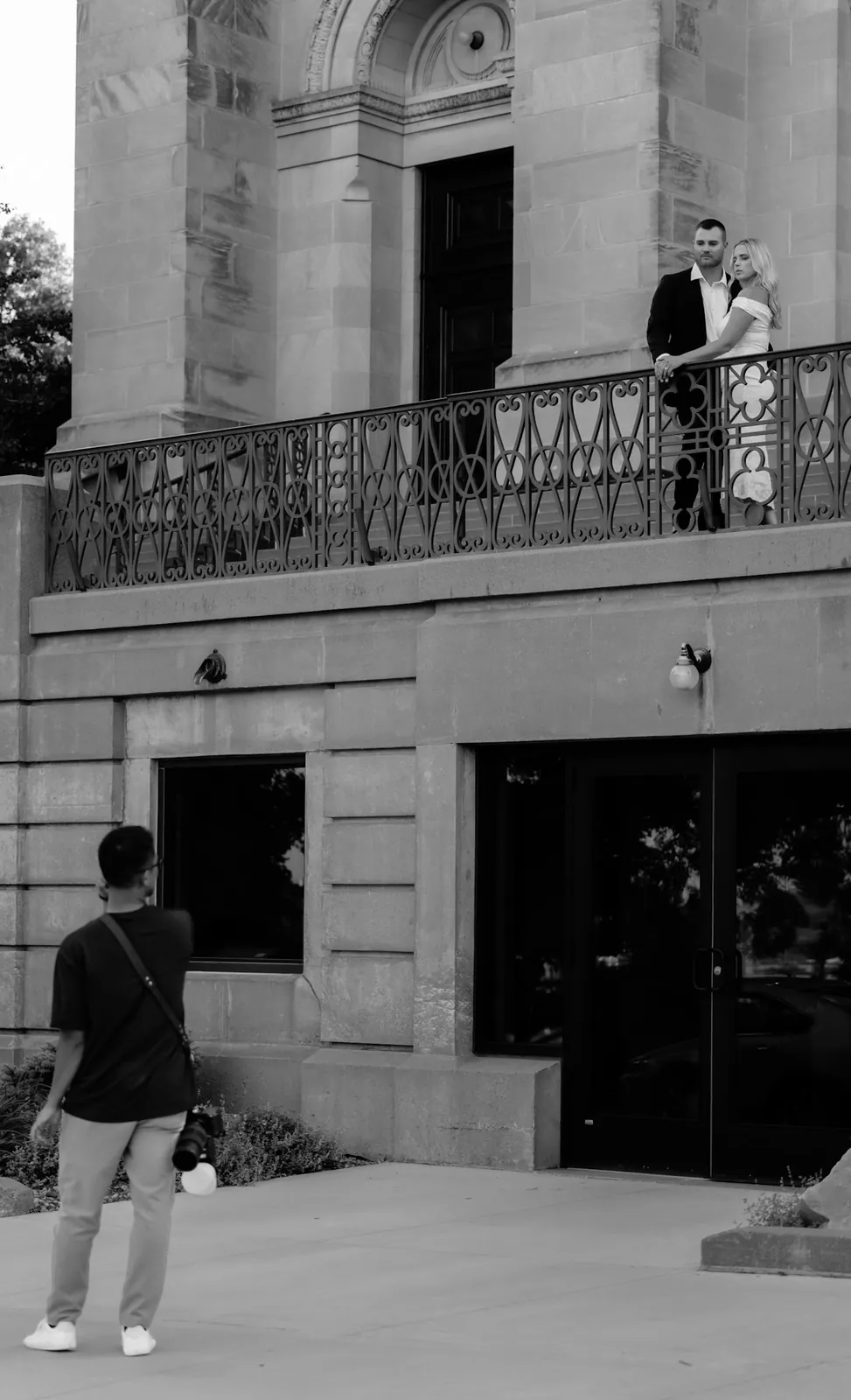 Black and white behind-the-scenes of photographer Lloyd D. shooting an engaged couple on a cathedral balcony, Sioux Falls SD