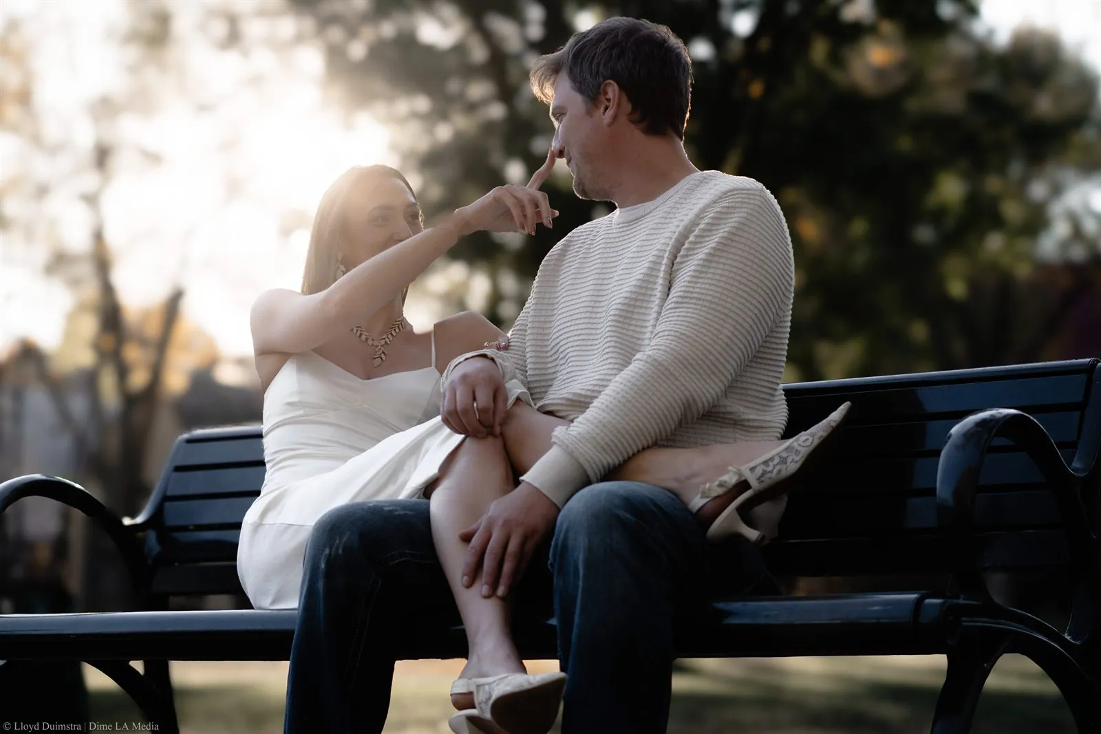 Woman playfully touching her fiance's nose in golden light