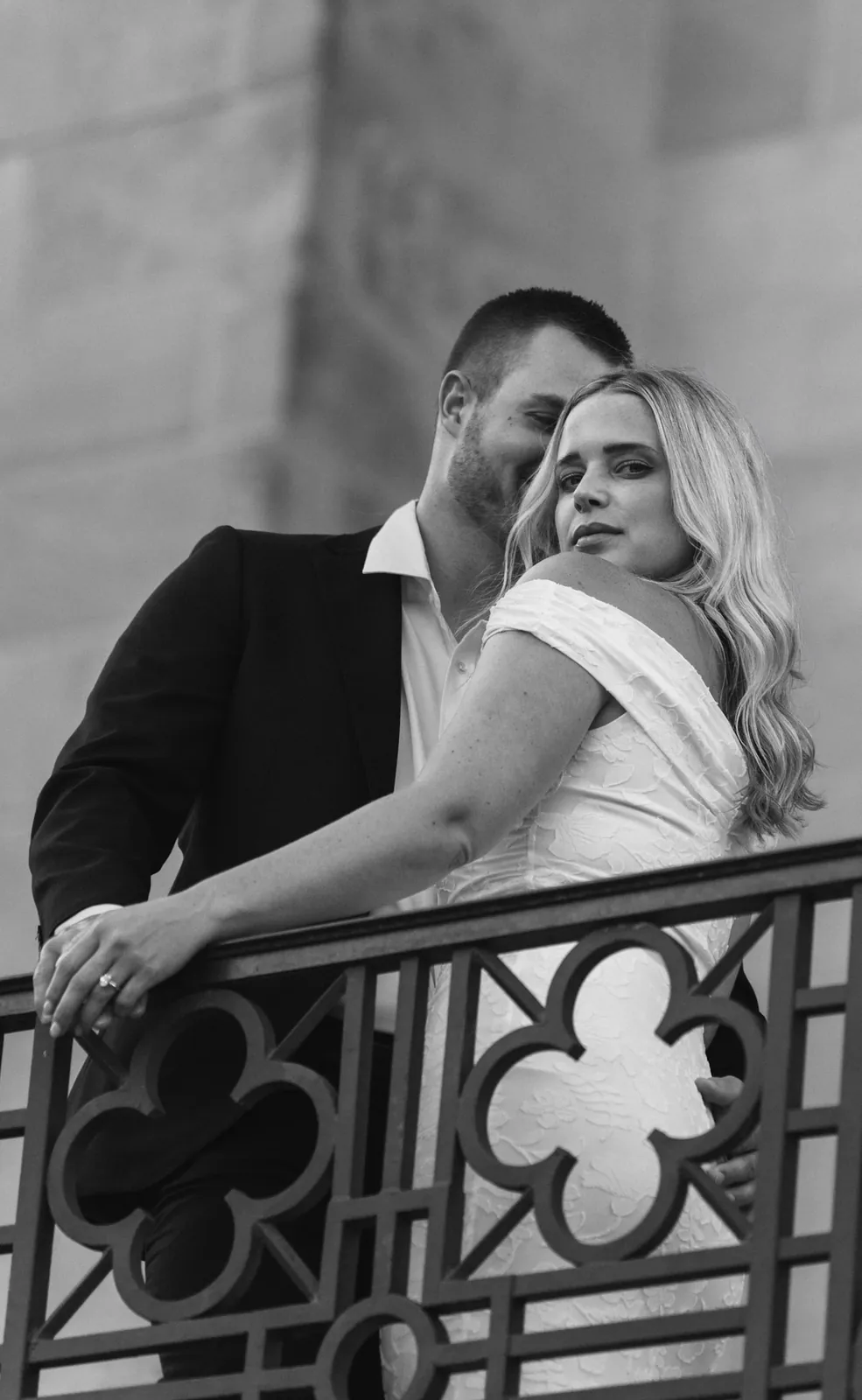 Black and white kiss on the forehead behind an iron quatrefoil railing
