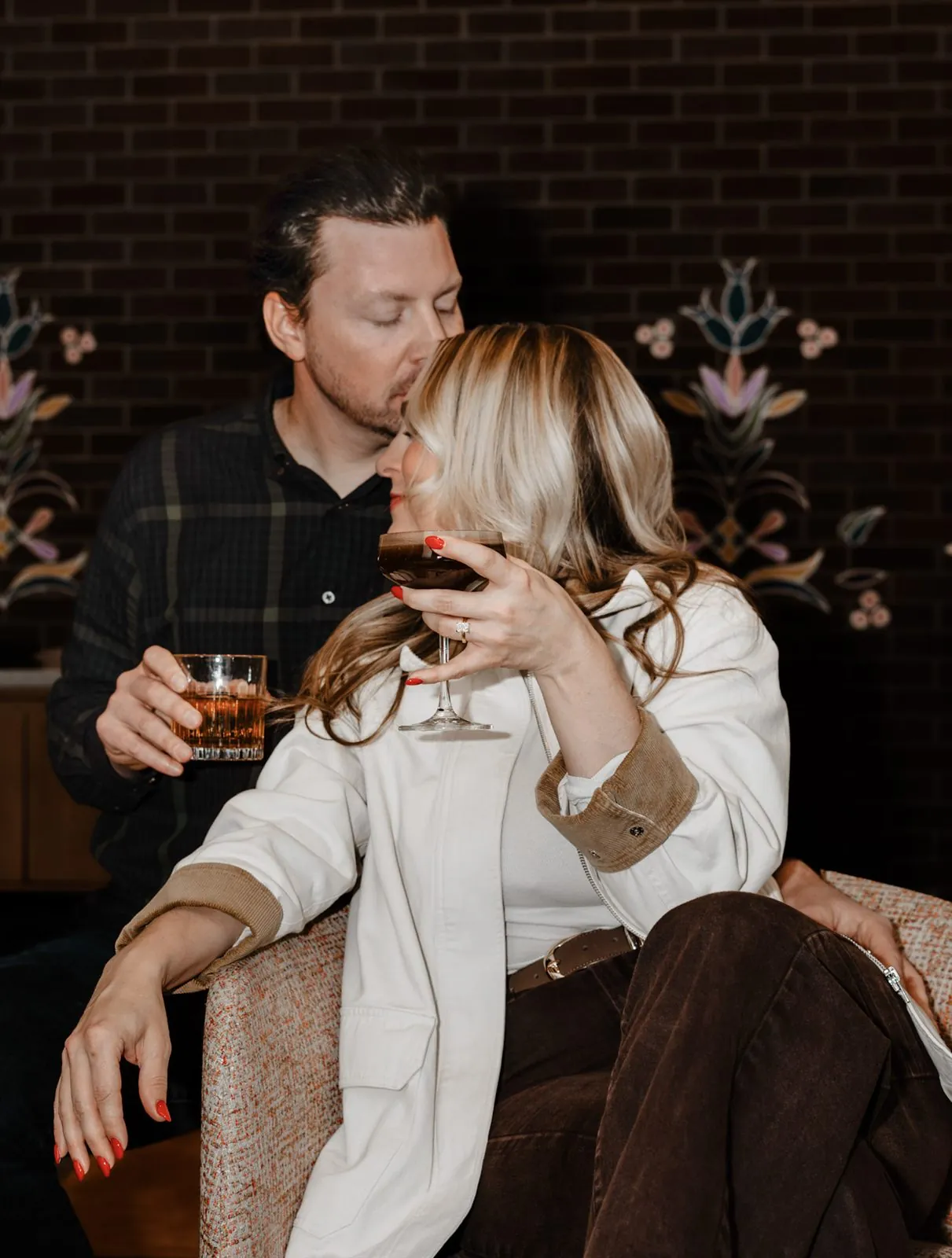 Man kissing his partner's head as she sips an espresso martini