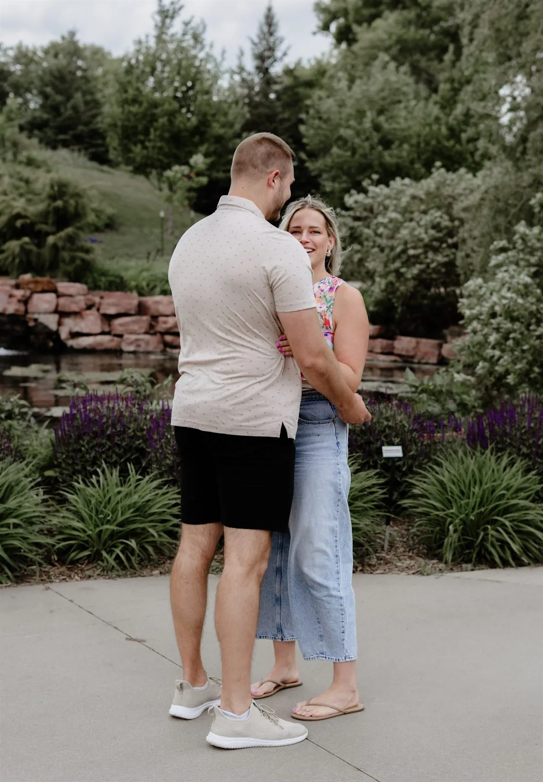 Couple embracing in a garden, bride-to-be smiling over his shoulder