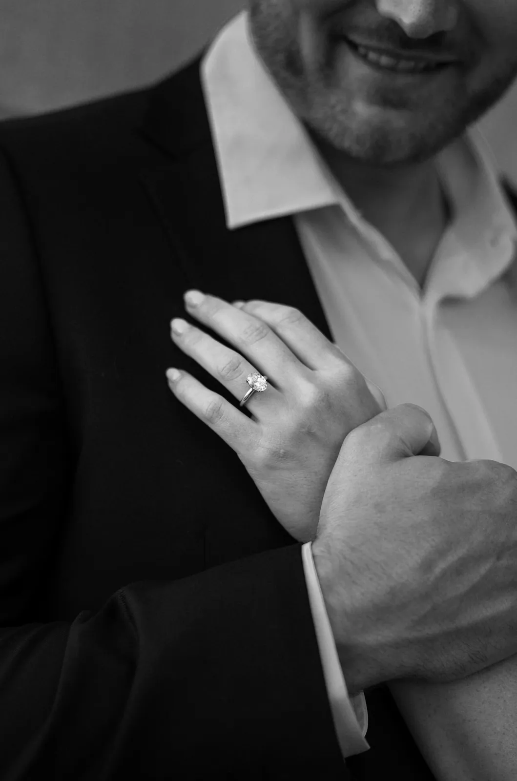 Black and white detail of the engagement ring resting on his chest