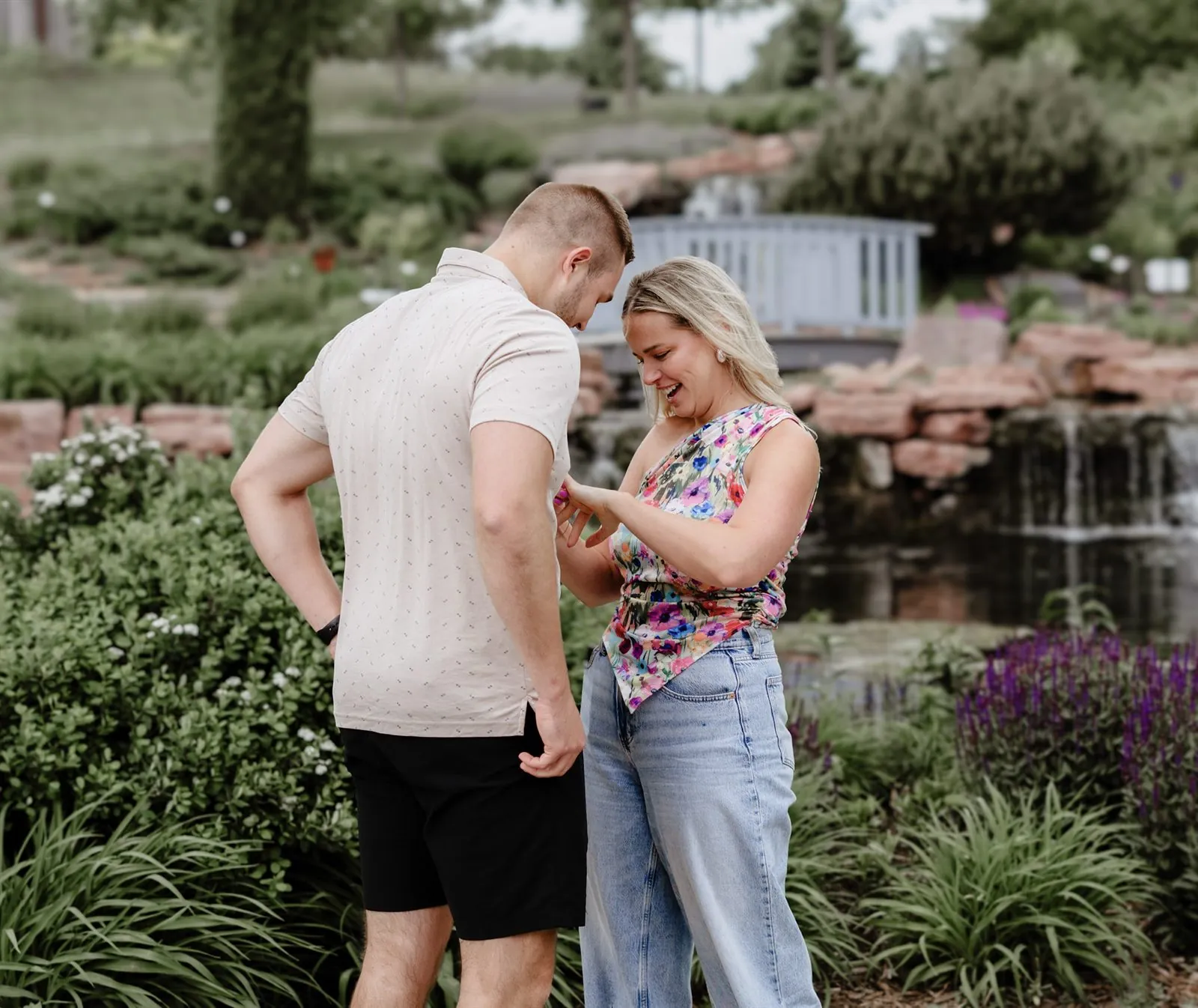 Couple admiring the new engagement ring by a garden waterfall
