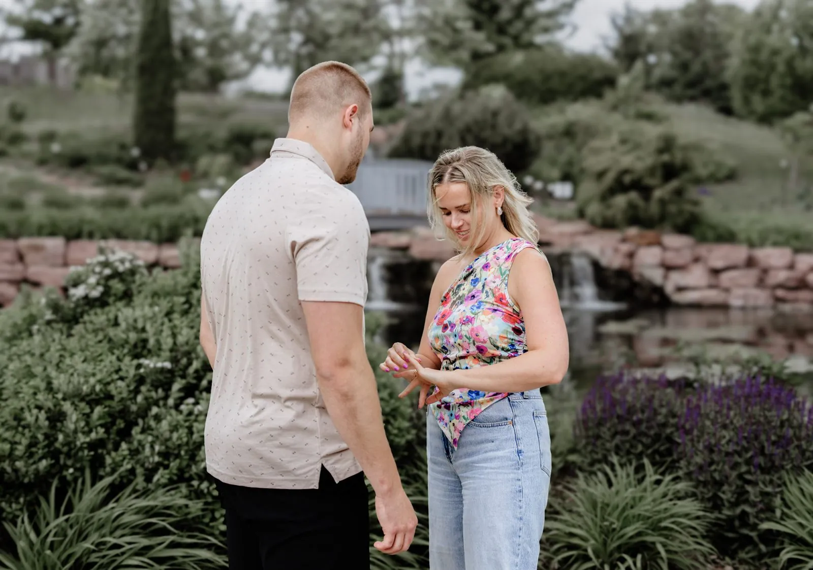 Woman showing off her engagement ring to her fiance in a garden