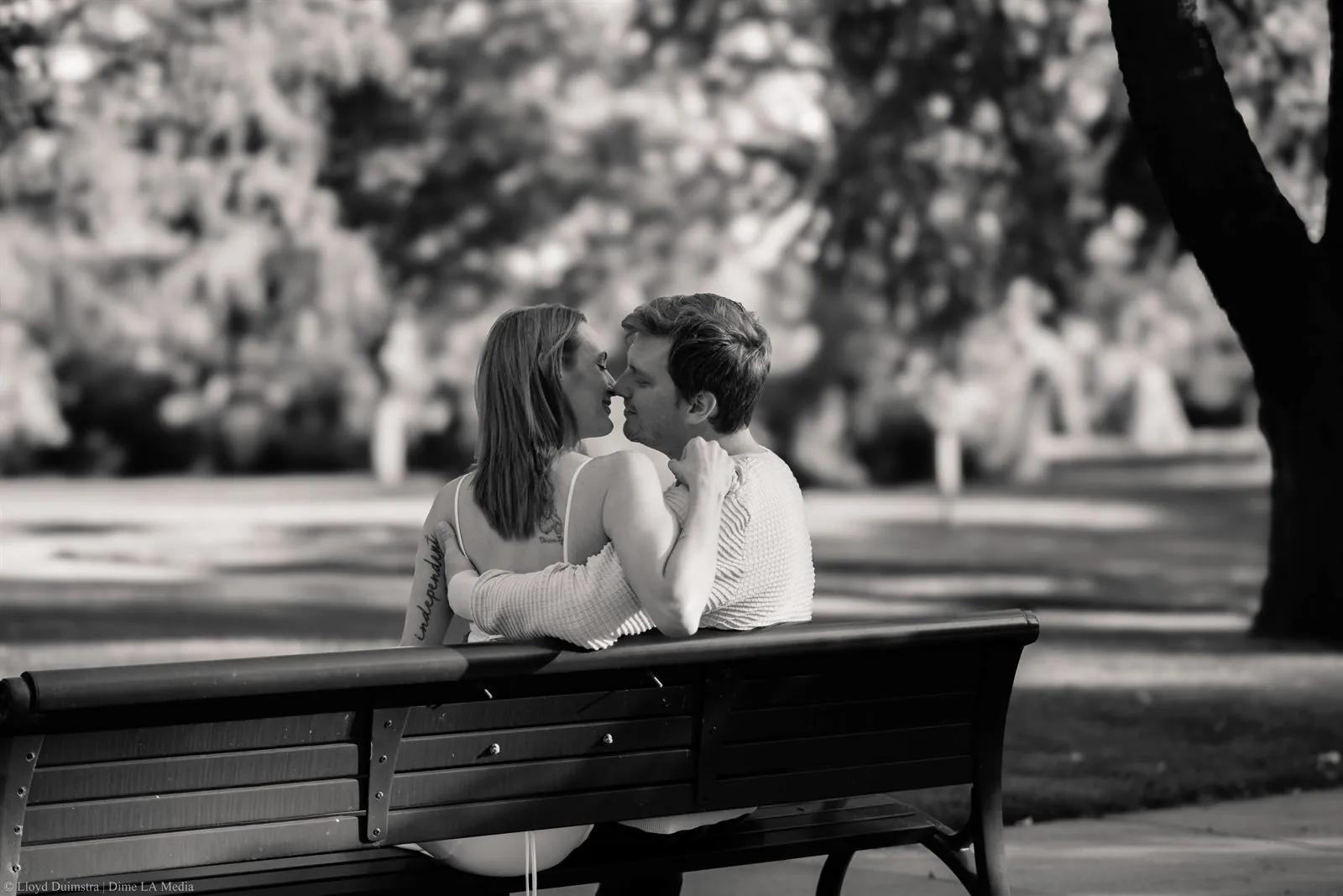 Black and white photo of a couple leaning close on a park bench
