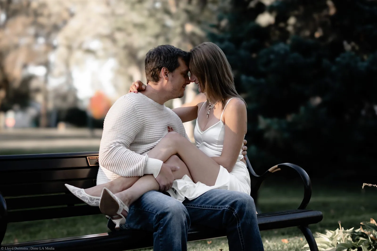 Engaged couple on a park bench with foreheads touching