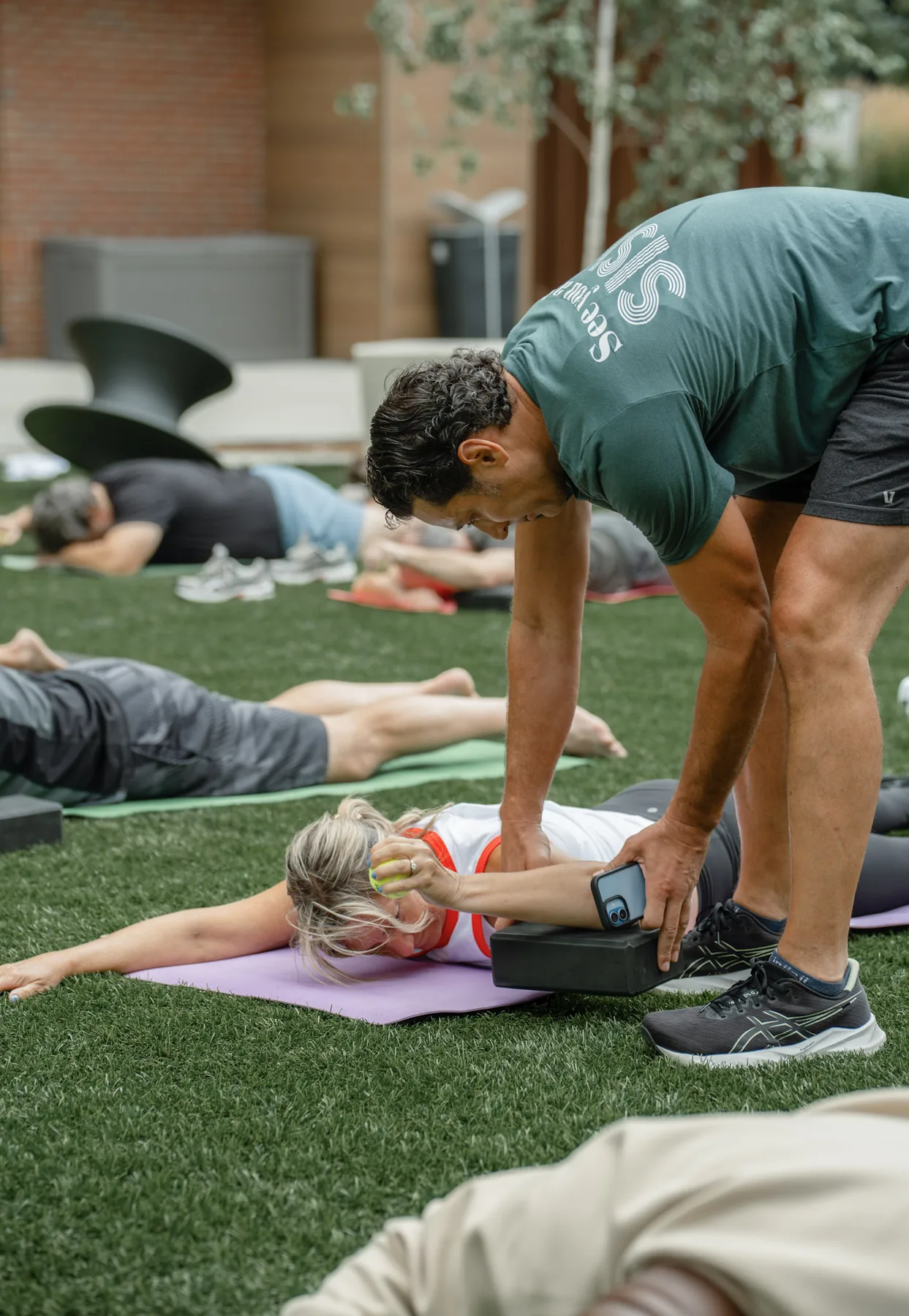 A Sisu coach guiding a participant through a Kinstretch hold on the lawn at Cherapa Place, Sioux Falls SD