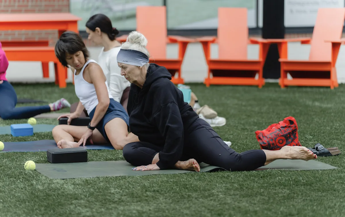 Participants working through a seated hold on the Cherapa Place lawn at the Sisu Kinstretch class, Sioux Falls SD