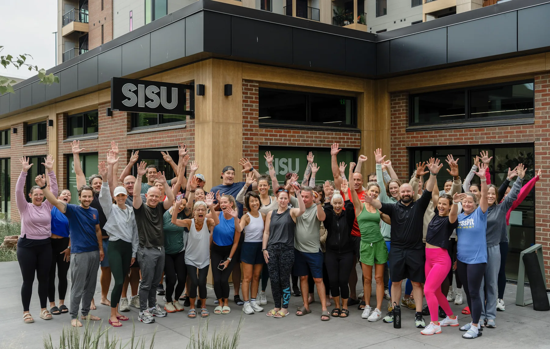 The full Kinstretch class throwing their hands up outside Sisu at Cherapa Place, photographed by Lloyd Duimstra, Sioux Falls SD
