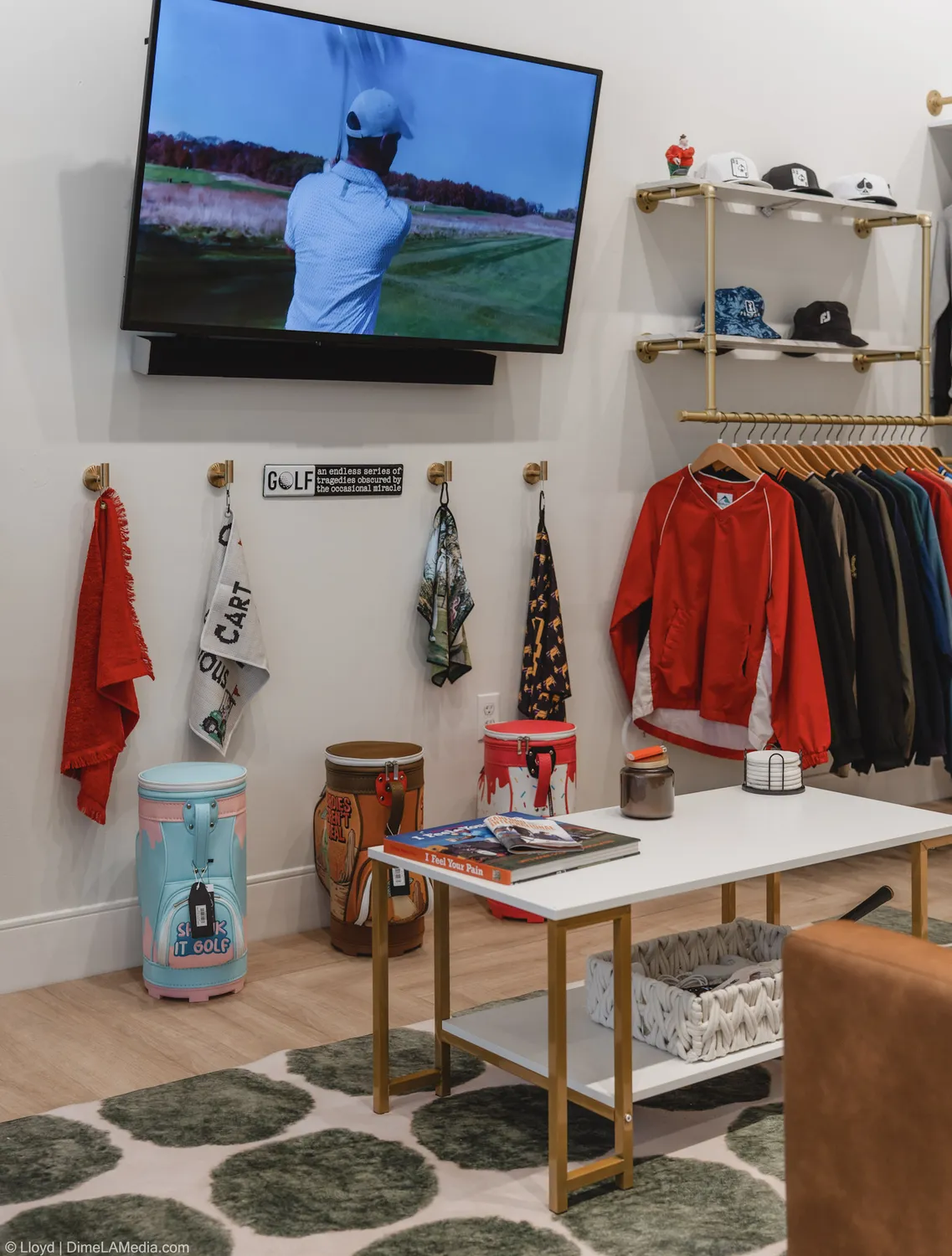 The lounge corner of Final Drive with a TV, apparel racks, and coffee table books