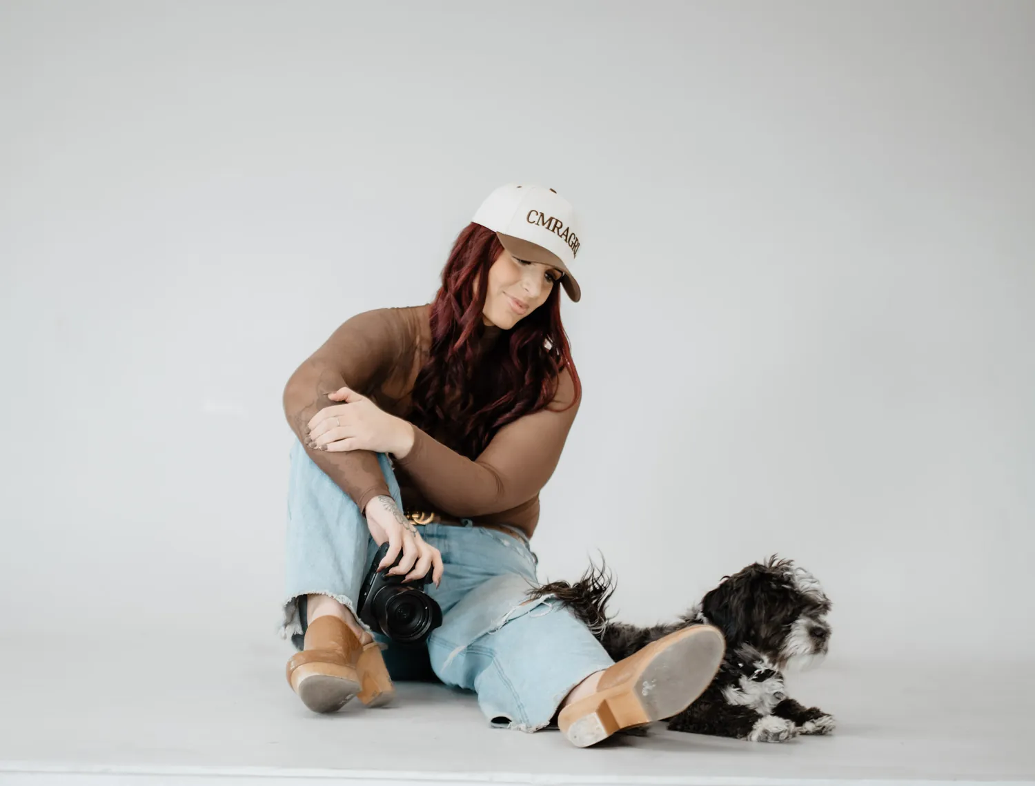 Jade sits on the studio floor with her dog lying beside her during the branding session