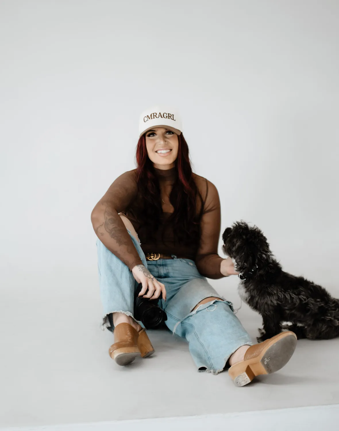 Jade smiles on the studio floor while her dog sits next to her