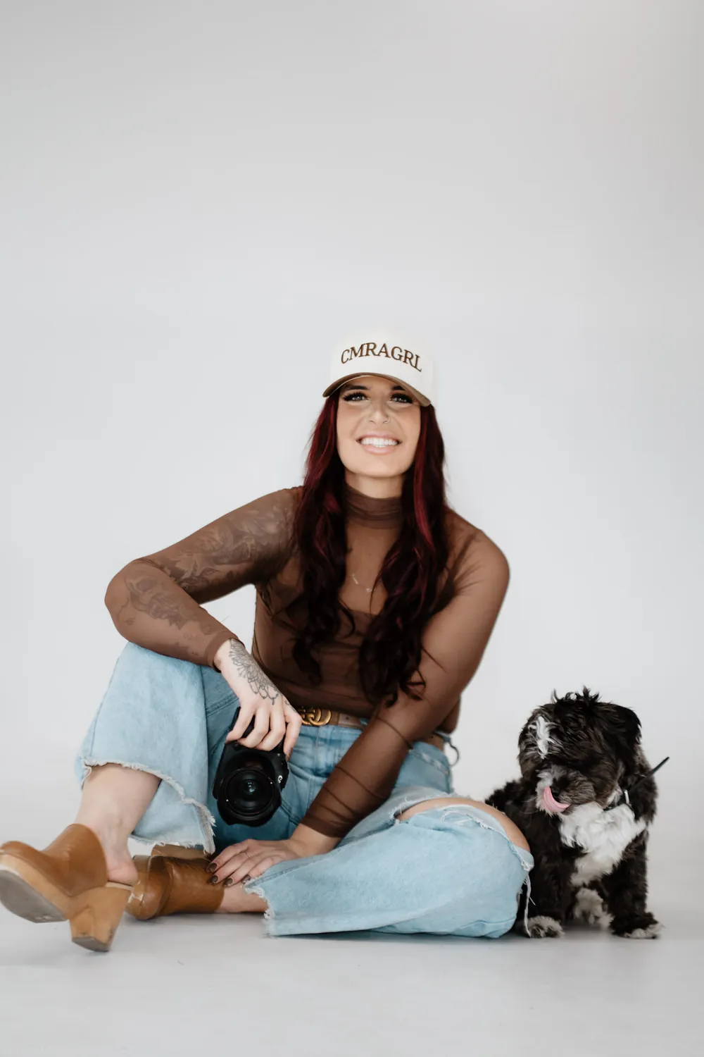 Jade laughs with her dog beside her on the white studio backdrop