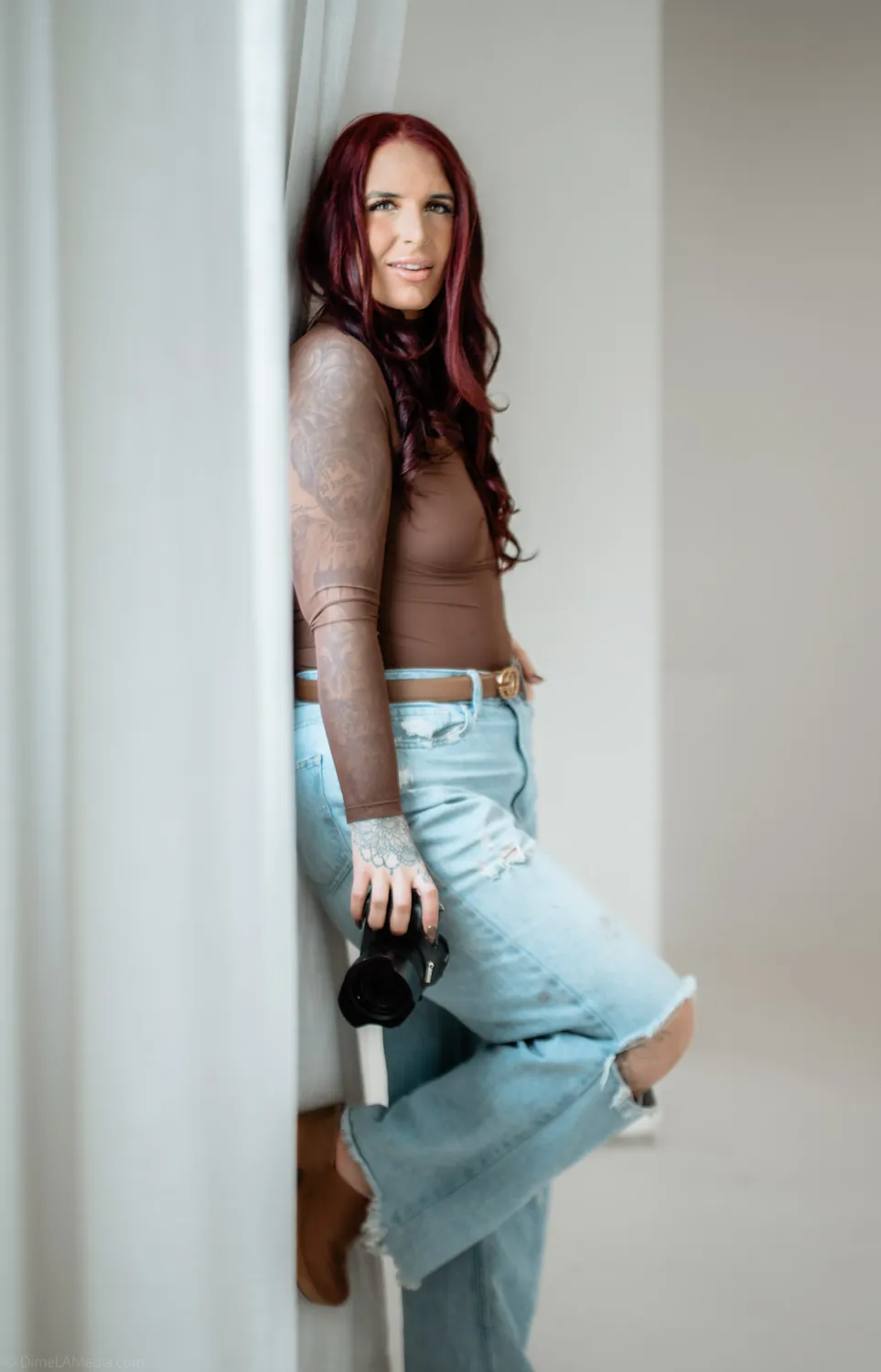 Jade, a Sioux Falls photographer, leans against the studio wall in window light during her personal branding session