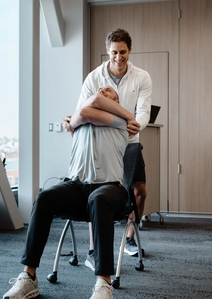 A Sisu coach working a seated client through a mobility position during an indoor workshop, Sioux Falls SD