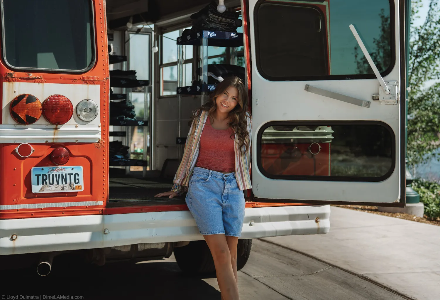 Maddie Theisen leans against the open tailgate of the True Vintage bus in the sun, downtown Sioux Falls