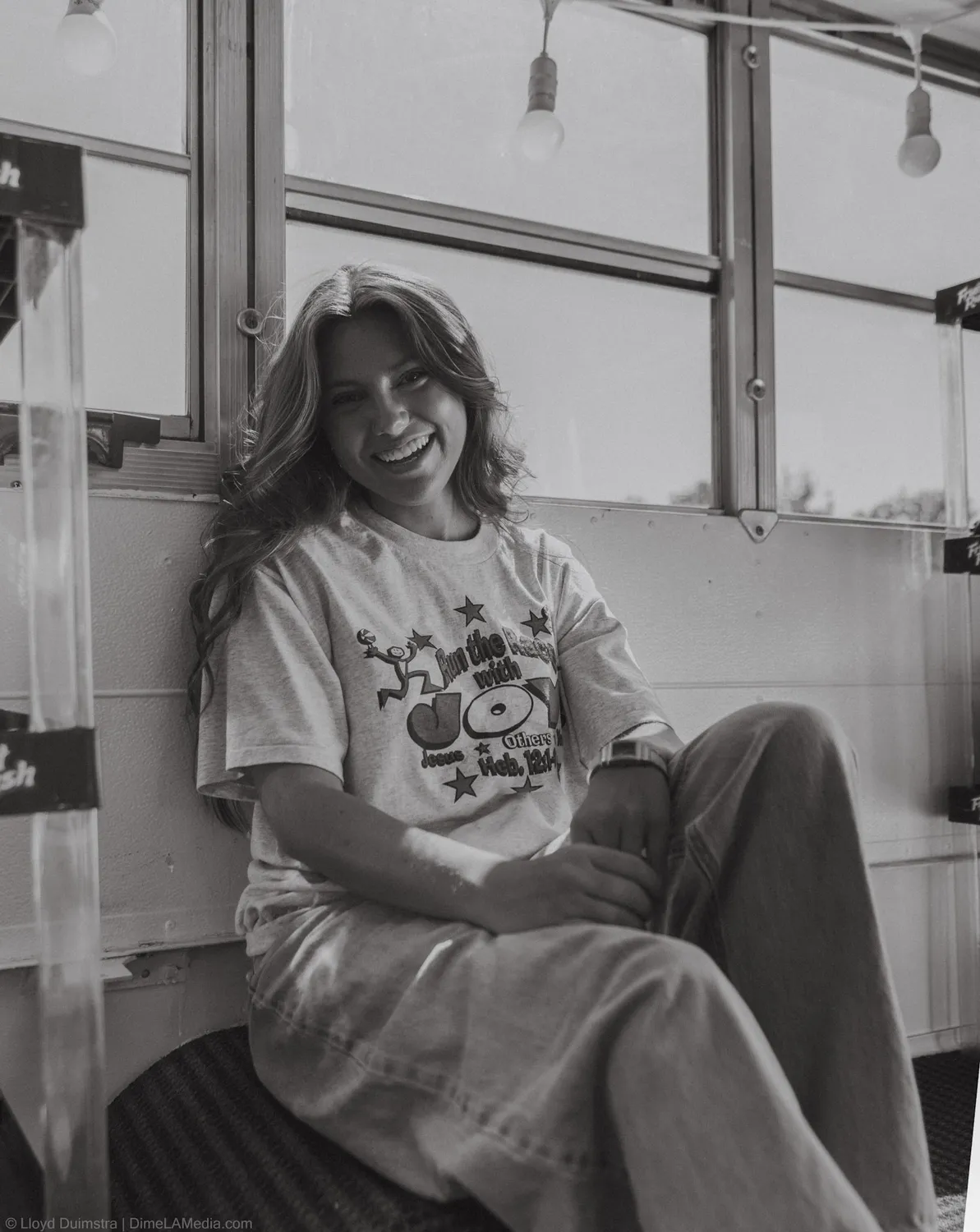 Black and white frame of Maddie Theisen laughing by the bus windows