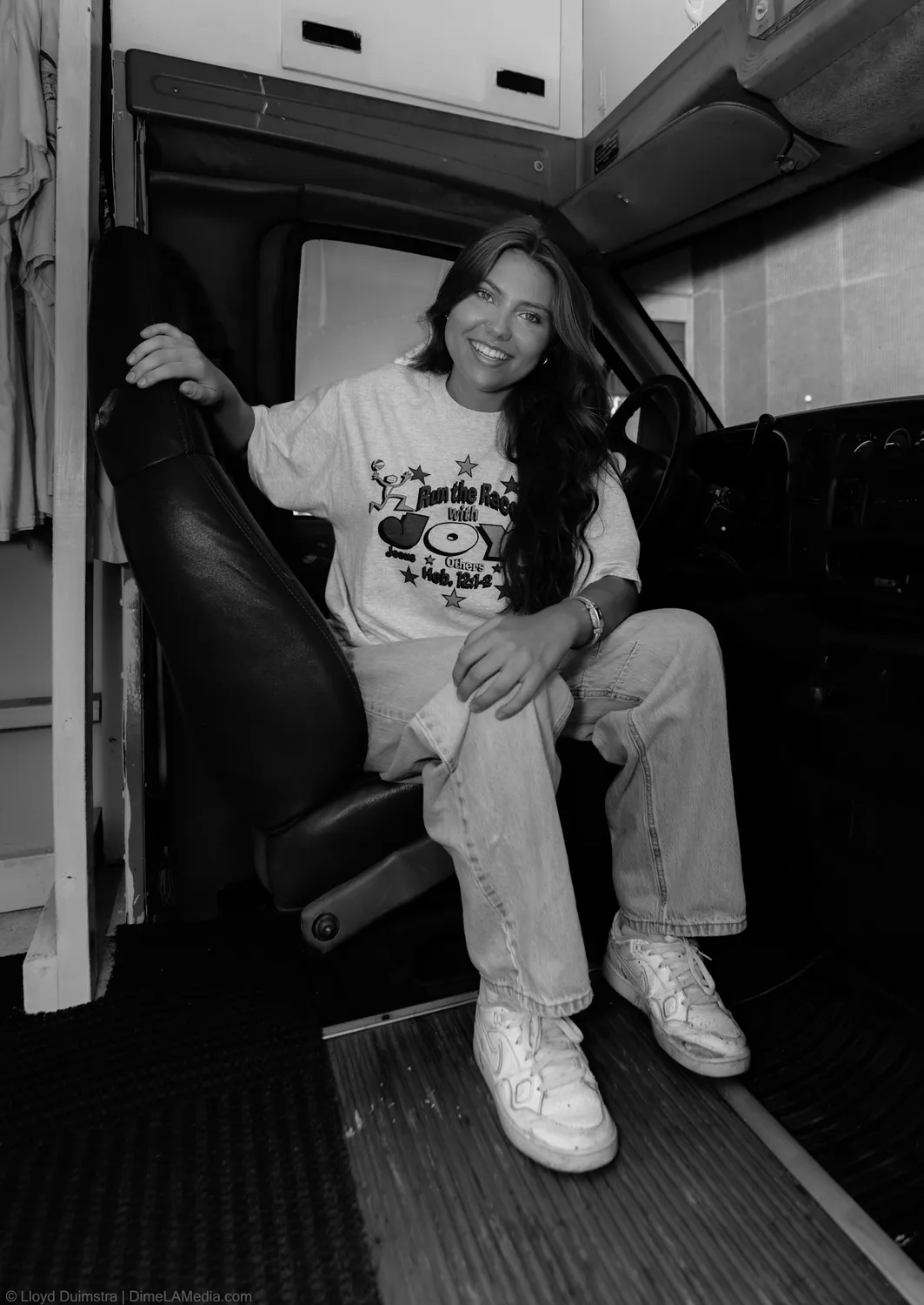 Black and white portrait of Maddie Theisen seated in a chair inside the True Vintage bus