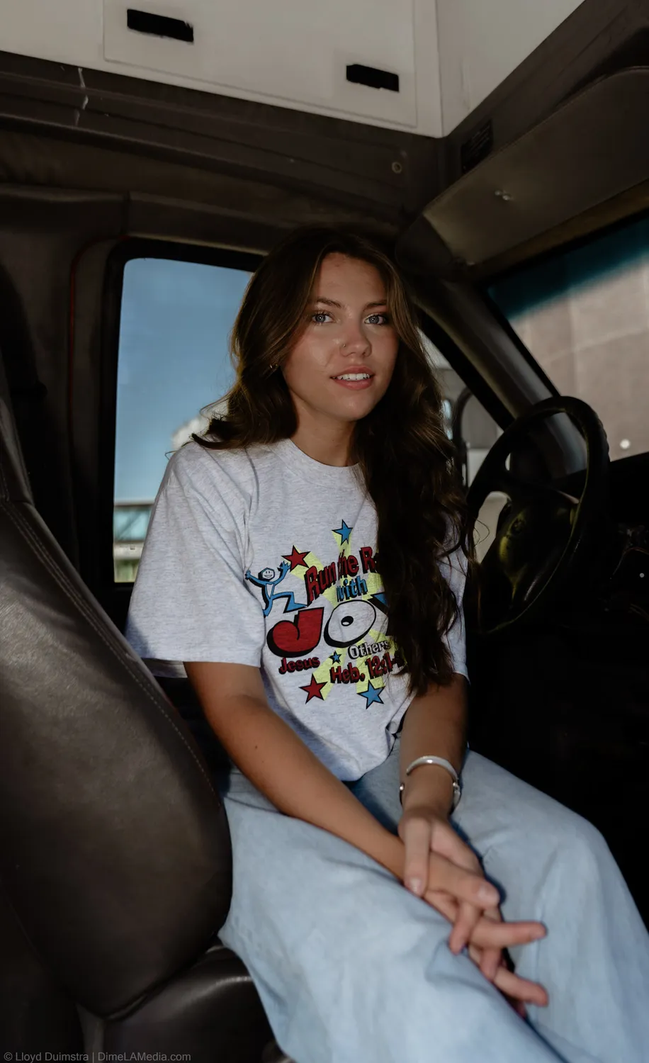 Founder portrait of Maddie Theisen seated in the cab of the True Vintage bus in a white tee