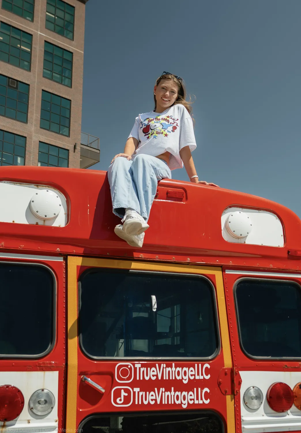 Maddie Theisen sits on top of the True Vintage bus against downtown Sioux Falls buildings
