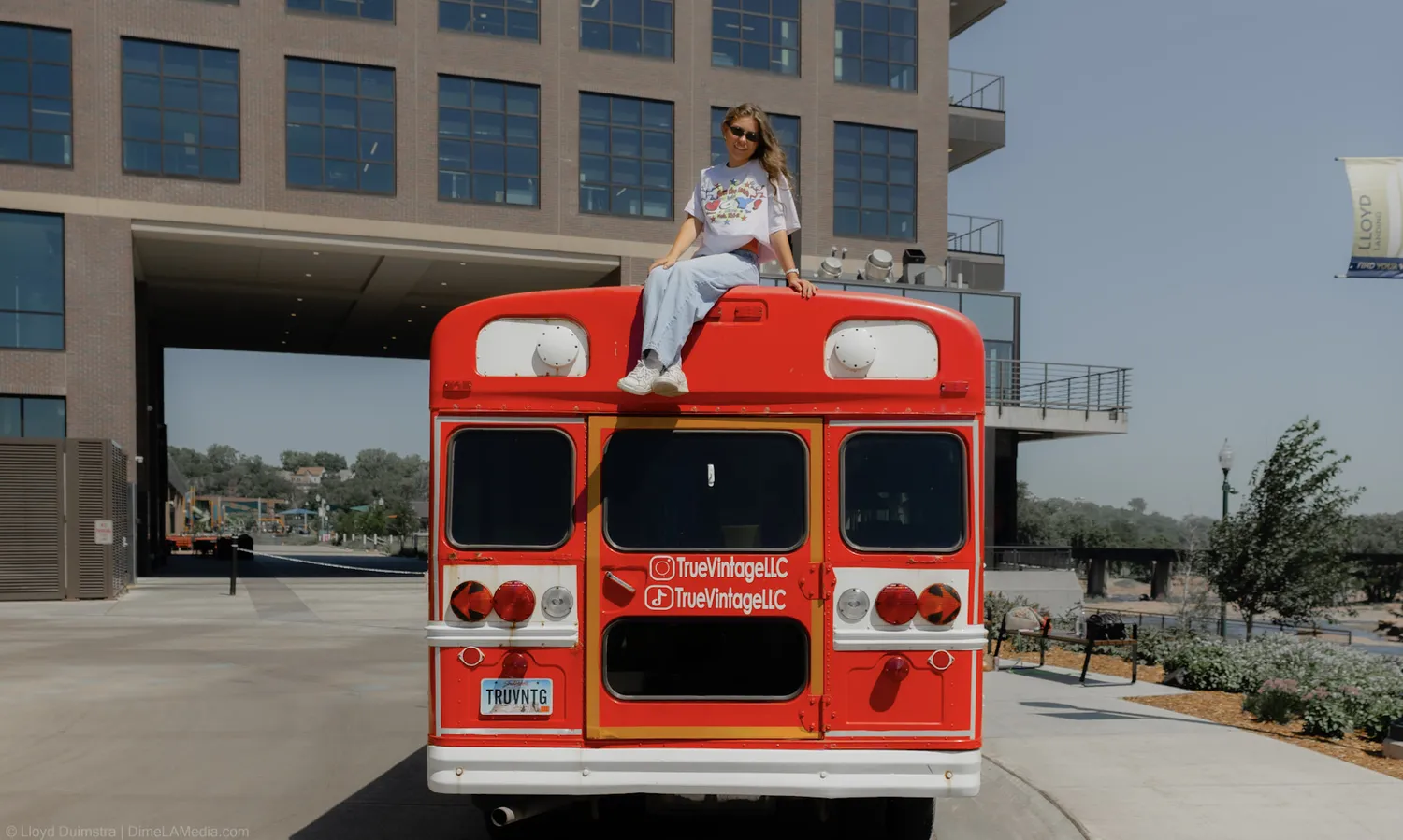The red True Vintage bus rolls down the road in Sioux Falls with Maddie on the roof