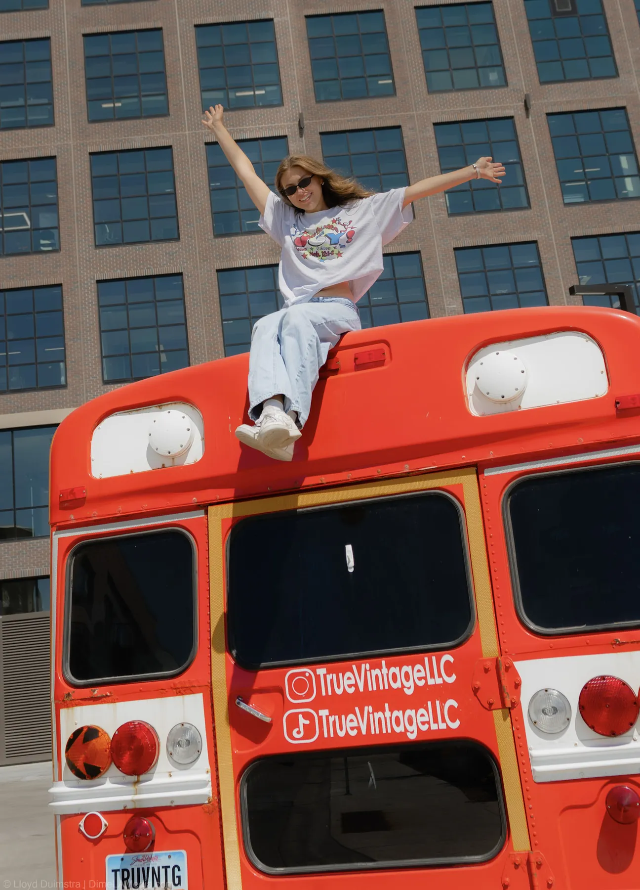 Maddie celebrating on top of the True Vintage bus, arms wide