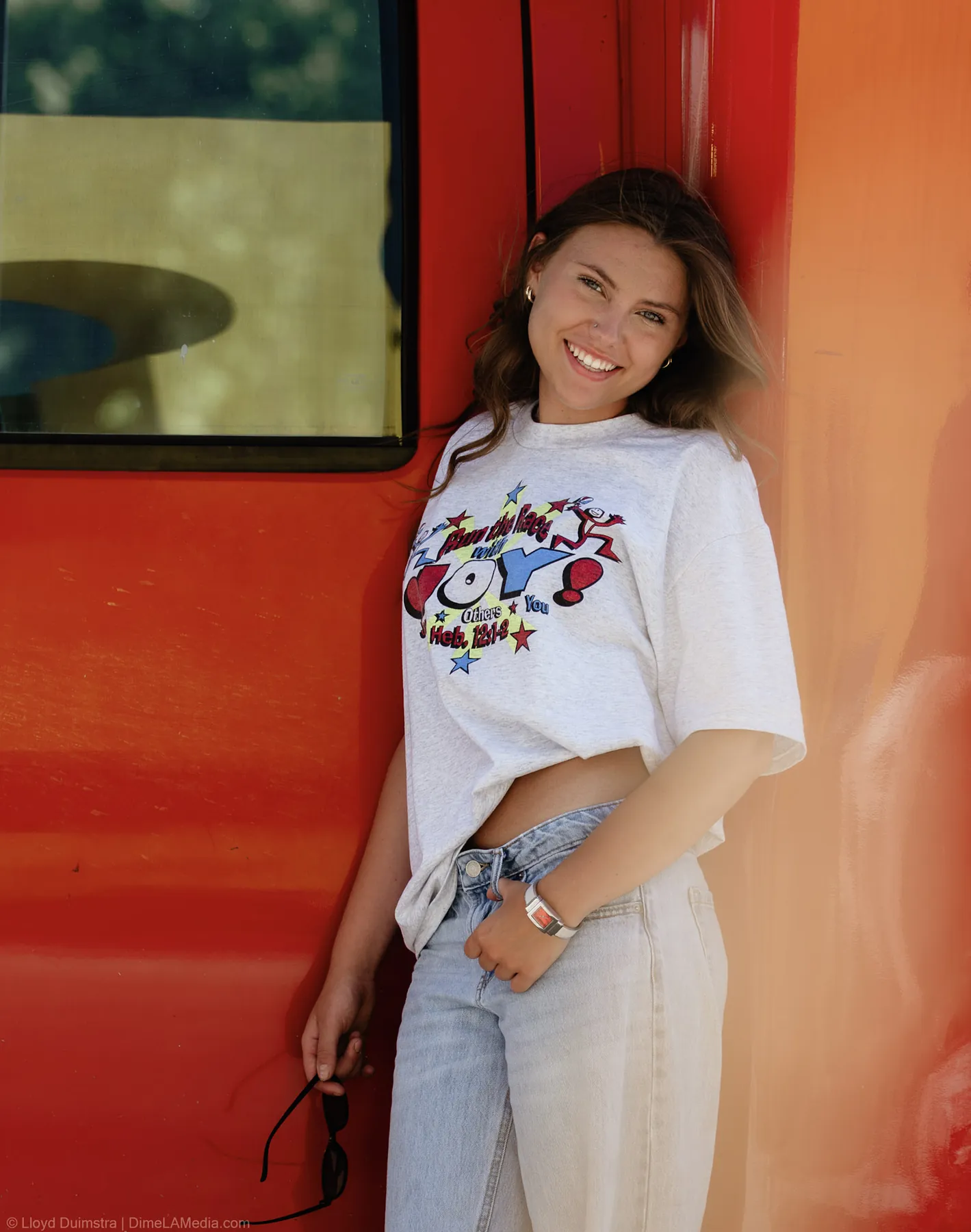 Maddie smiling against the red True Vintage bus door