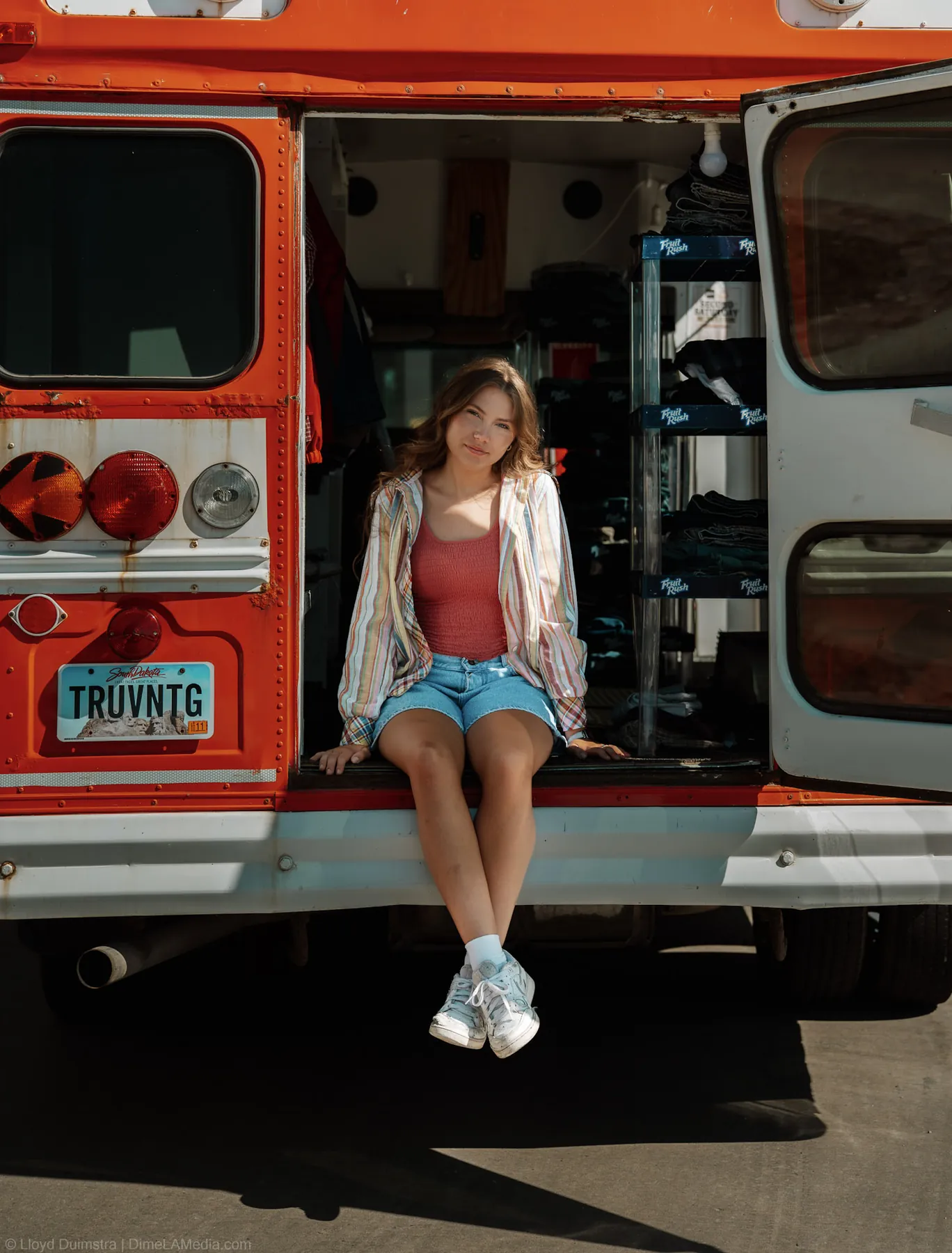 Maddie seated in the back doorway of the orange and red bus