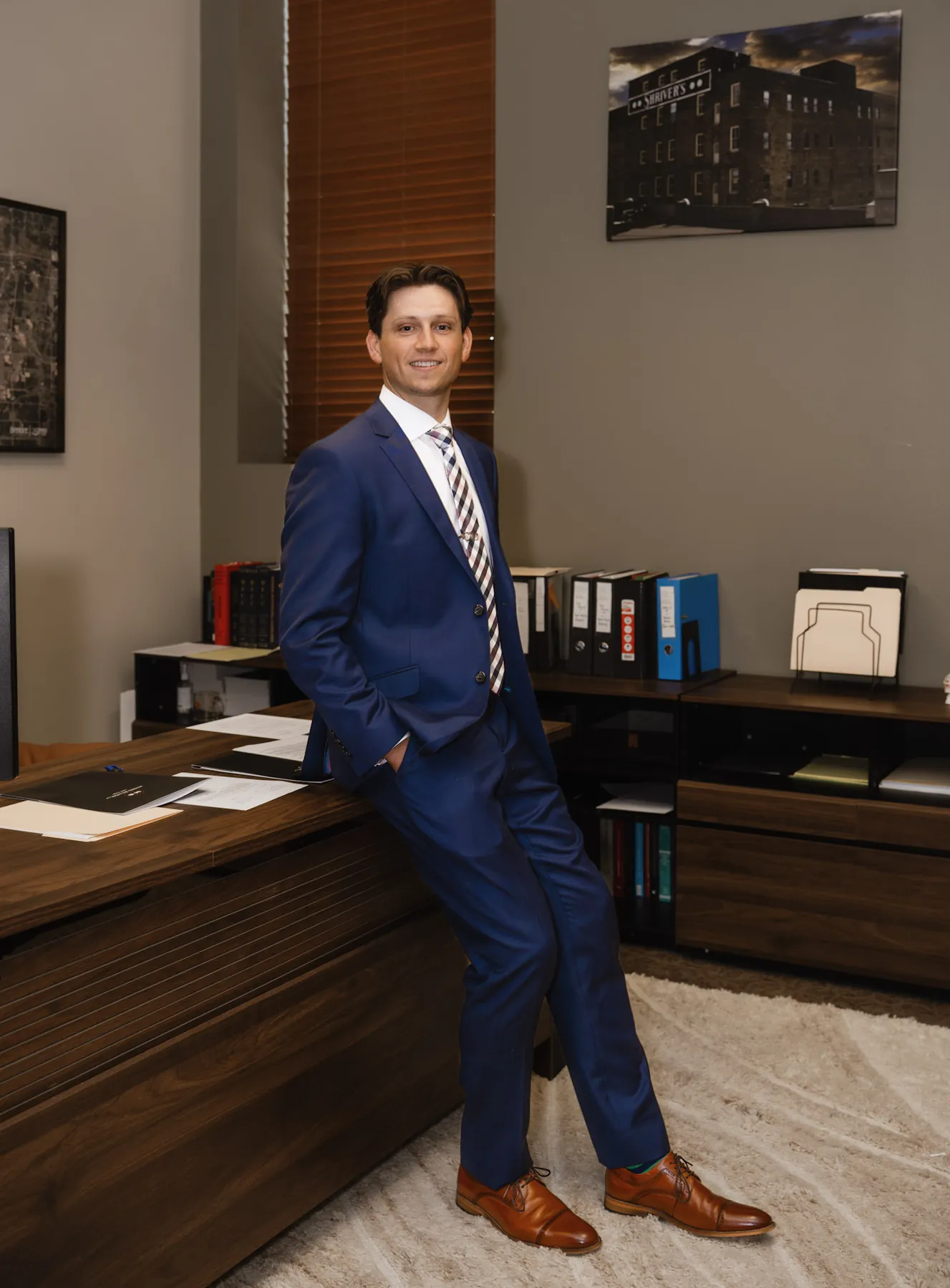 Environmental portrait of an attorney leaning on his desk in a Sioux Falls office