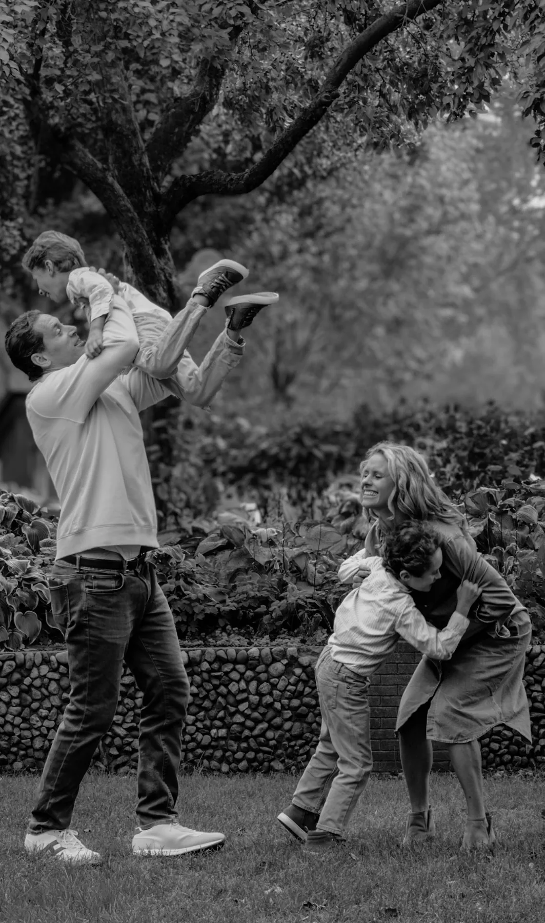 Black and white candid of parents playing with their sons